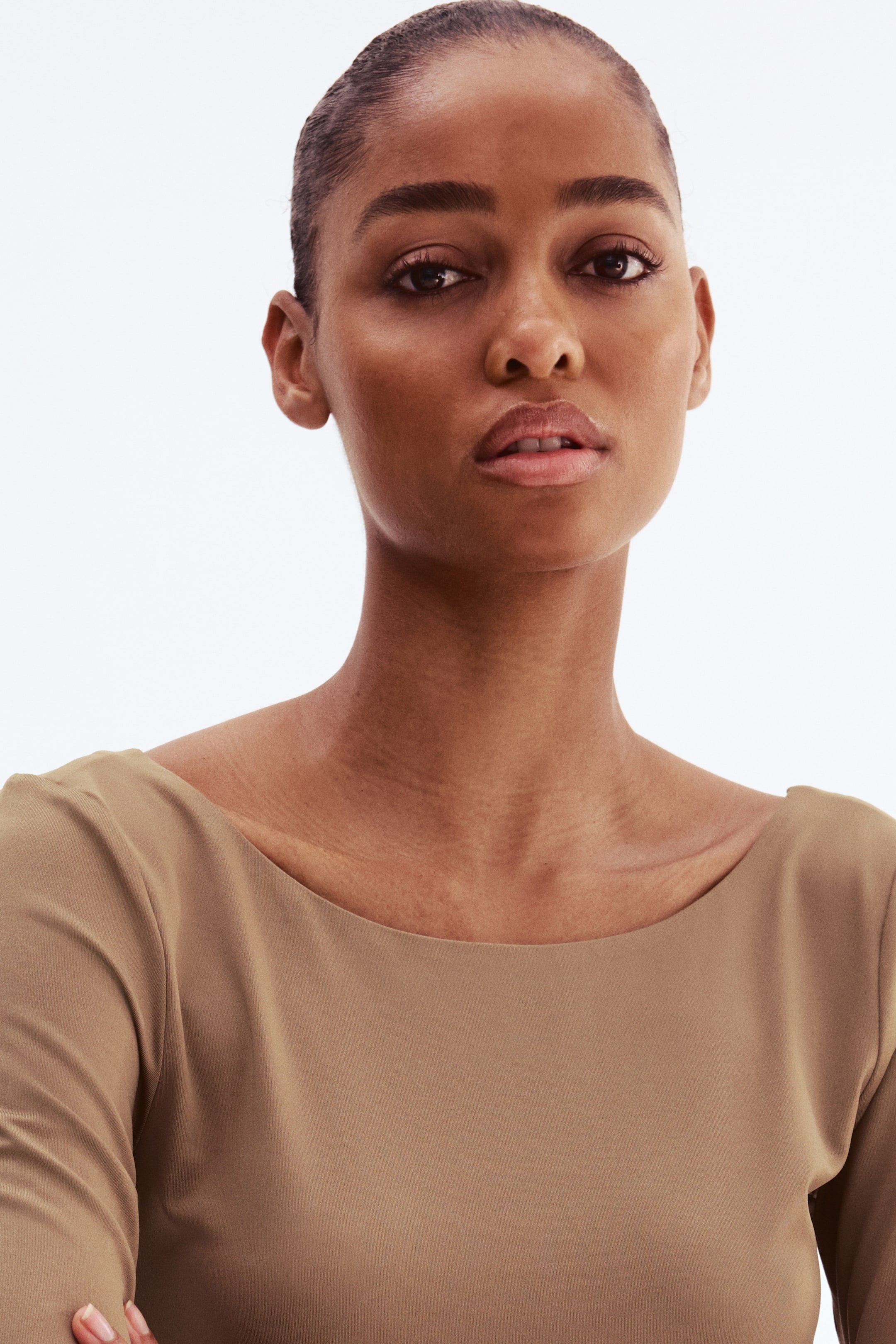 View larger image: A tan top features a wide boat neck and long sleeves. It fits smoothly across the shoulders and chest.