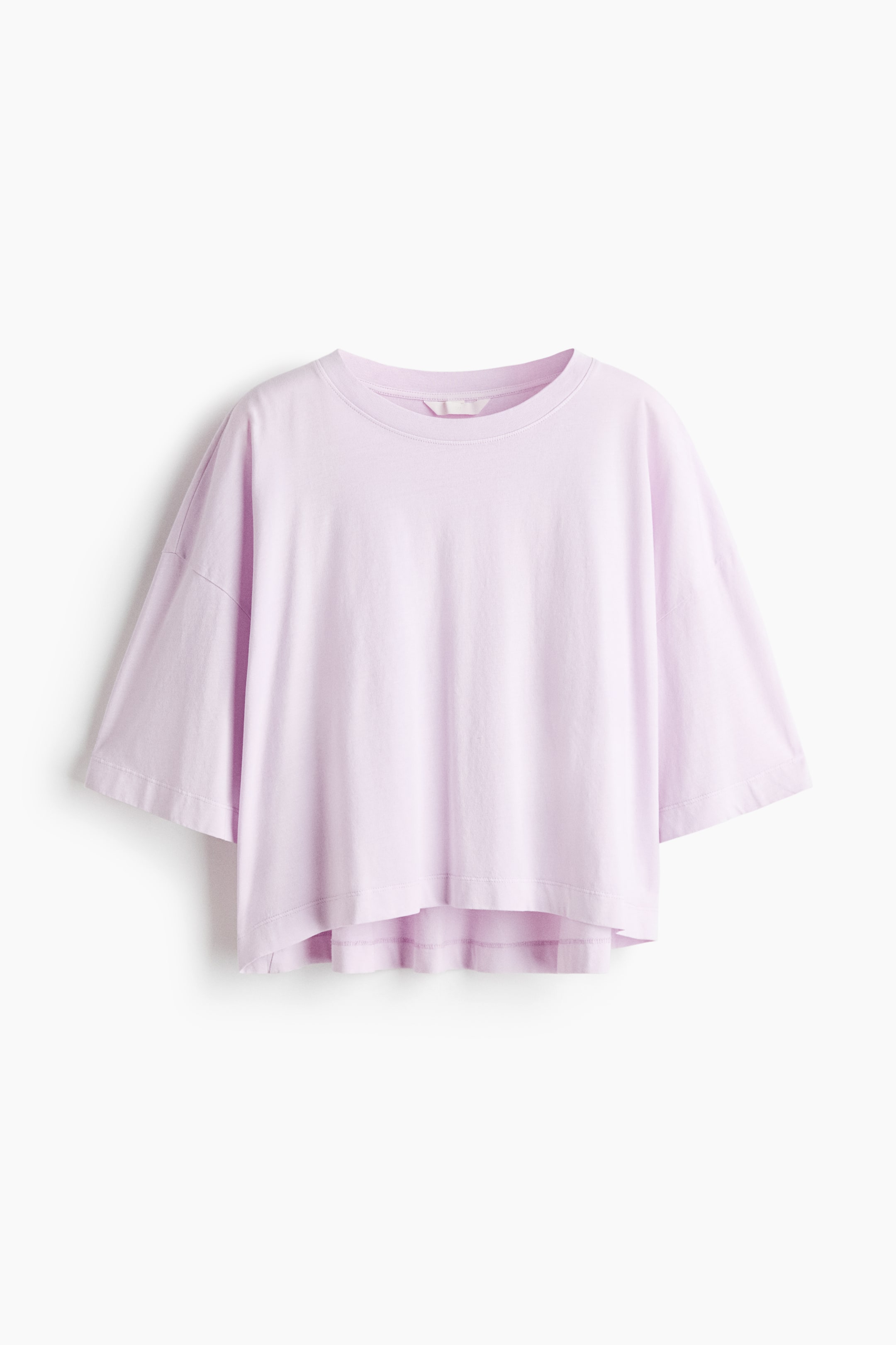 View larger image: A lavender t-shirt is facing front, featuring a crew neck and wide, short sleeves with dropped shoulders. It is showing a loose, boxy fit, a cropped length, and a high-low hem.