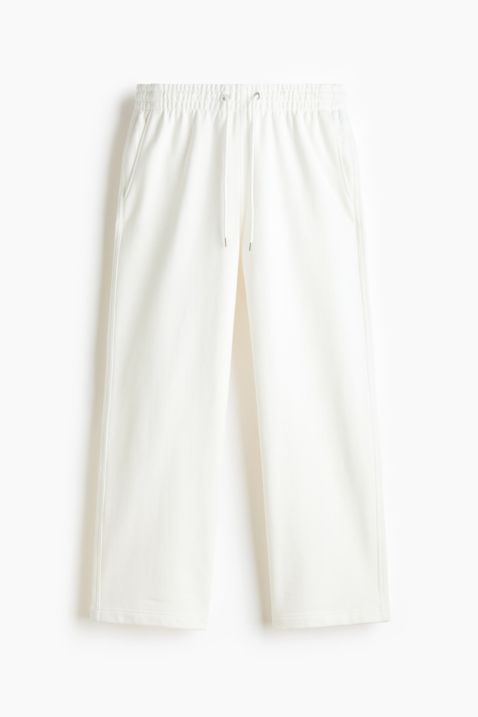 Off-white track pants are shown from the front, featuring a loose fit with straight-cut legs and clean-finished hems. The pants display an elasticated waistband with adjustable drawstrings and side-seam pockets. - 1