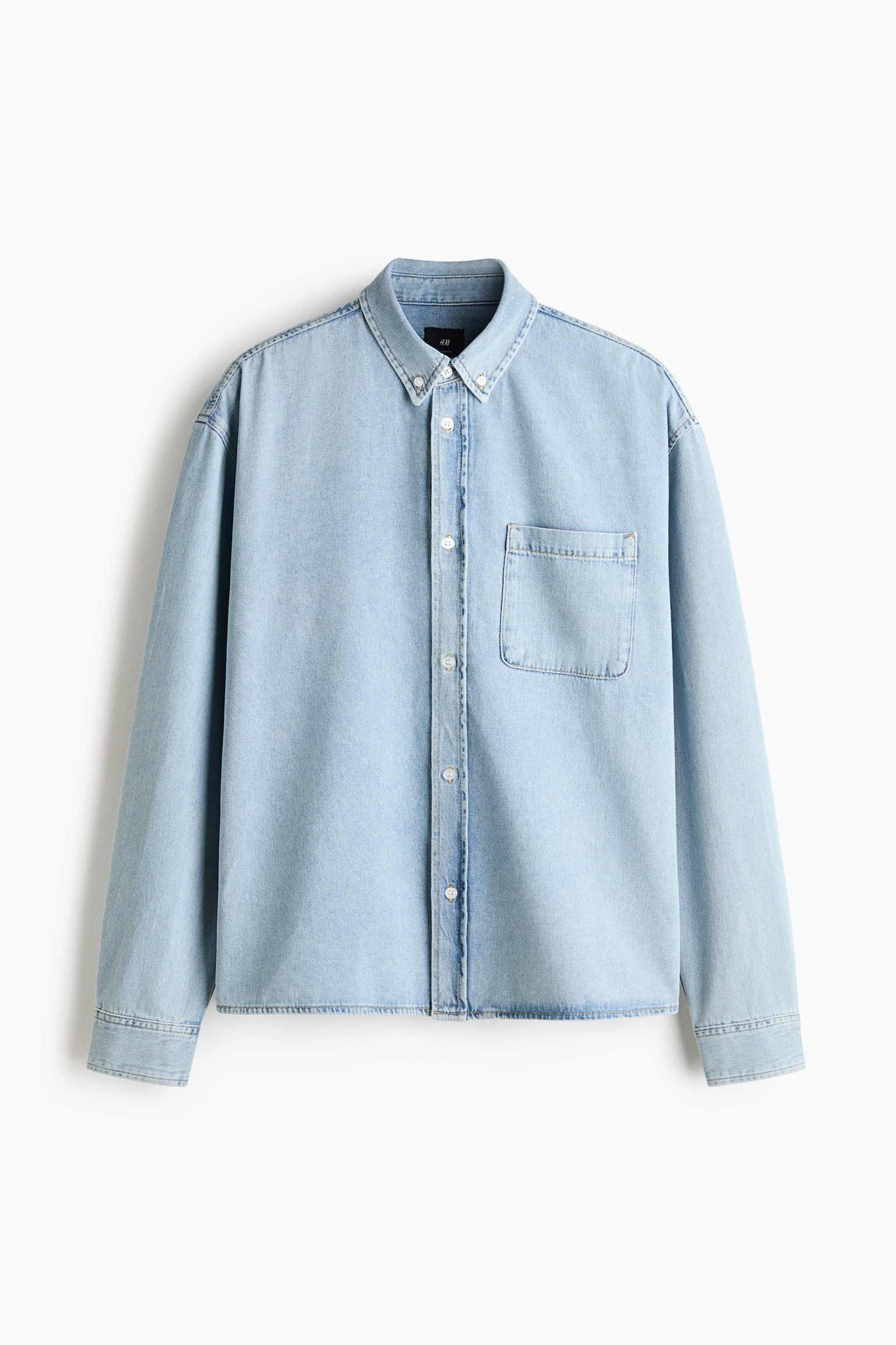 Ein hellblaues Denimhemd hÃ¤ngt mit der Vorderseite nach vorne und verfÃ¼gt Ã¼ber einen Button-down-Kragen, eine durchgehende Knopfleiste in der Mitte und eine einzelne aufgesetzte Brusttasche auf der linken Seite. Das Hemd zeigt lange Ãrmel mit geknÃ¶pften Manschetten und einen geraden Saum.