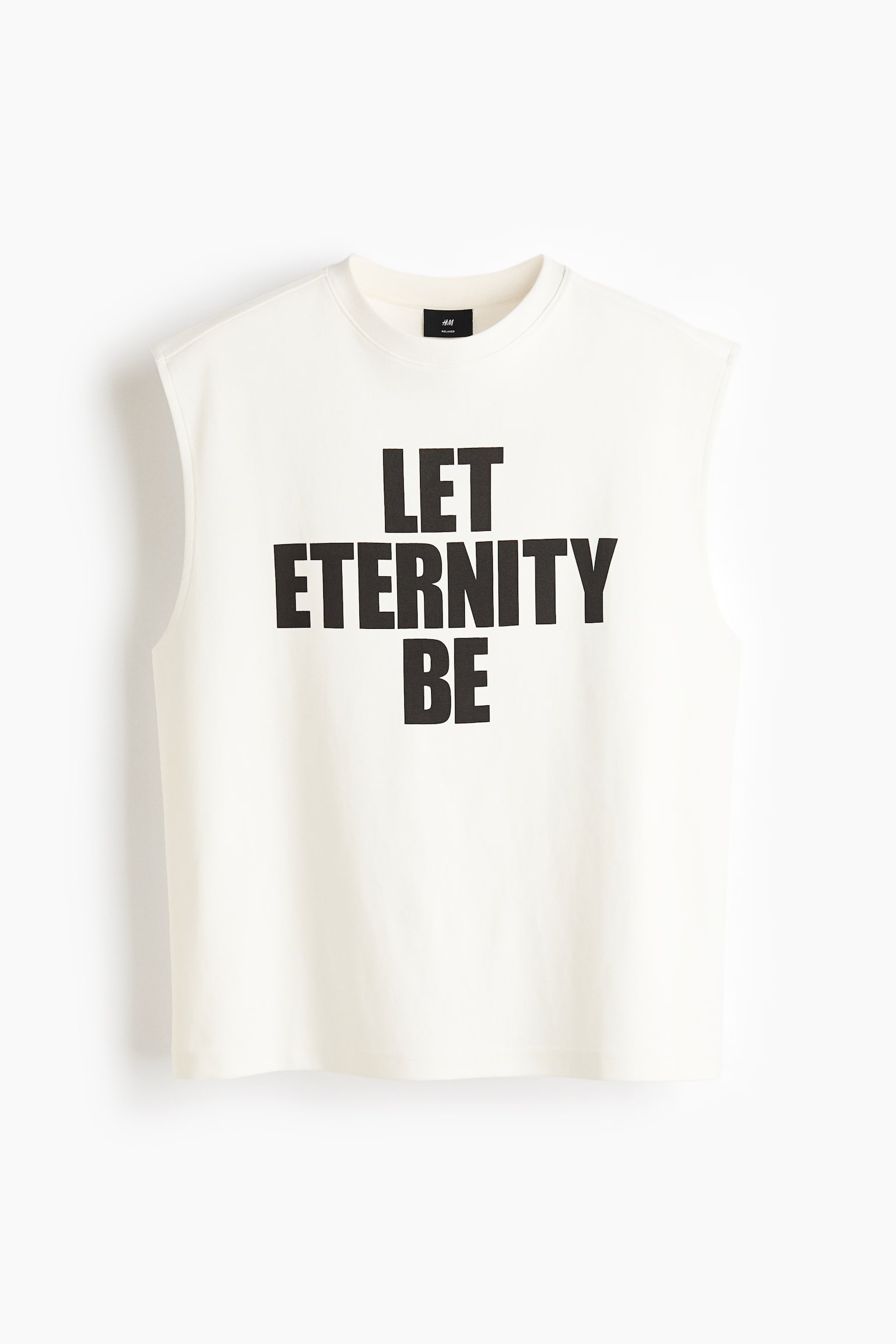 오프 화이트 민소매 탑 전면에 "LET ETERNITY BE"라는 검은색 그래픽 프린트가 있습니다. 이 제품은 골지 크루넥과 넓고 마감된 암홀을 특징으로 합니다. - 1