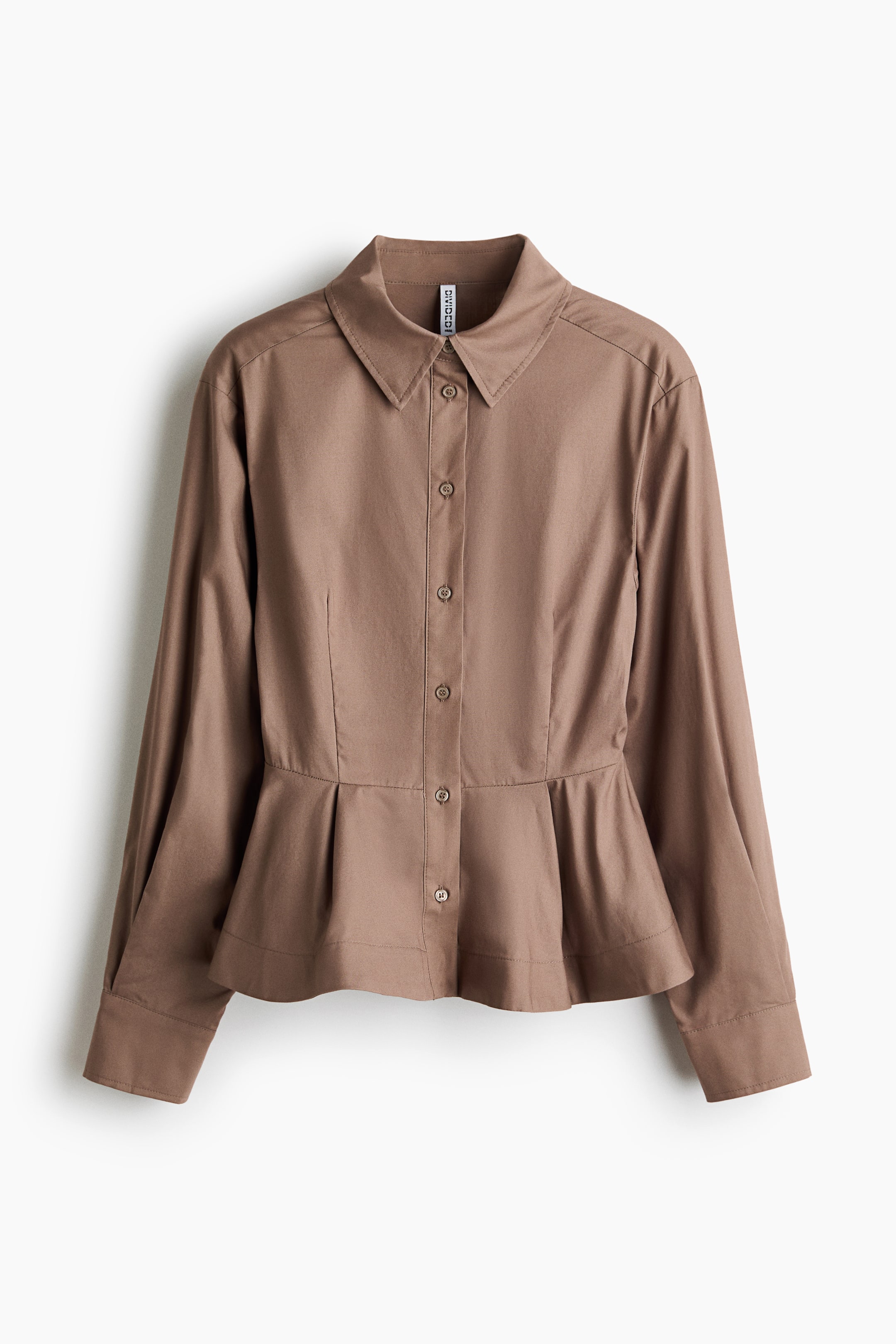 View larger image: A brown shirt is displayed in a front view, crafted from crisp cotton poplin fabric, featuring a collar and buttons running down the front. It highlights forward-facing shoulder seams and long sleeves with pleats for added volume, ending in tapered, buttoned cuffs. Shaping seams define the silhouette at the front, transitioning into a flared, pleated peplum.