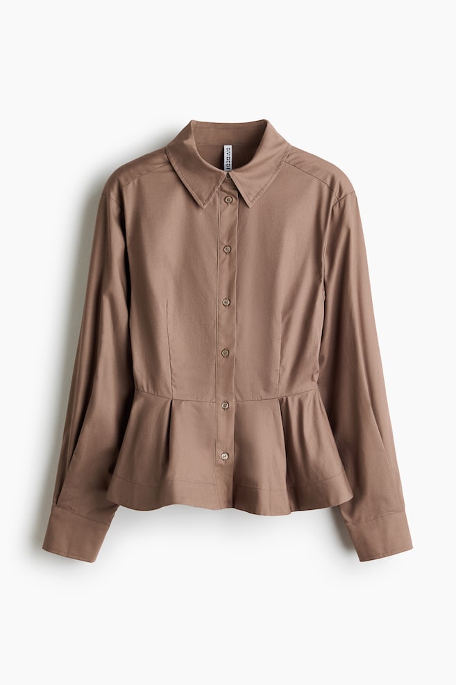 A brown shirt is displayed in a front view, crafted from crisp cotton poplin fabric, featuring a collar and buttons running down the front. It highlights forward-facing shoulder seams and long sleeves with pleats for added volume, ending in tapered, buttoned cuffs. Shaping seams define the silhouette at the front, transitioning into a flared, pleated peplum. - 1