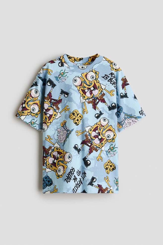 This light blue cotton jersey t-shirt is displaying from the front, featuring an all-over cartoon character graphic print. It is designed with a round, rib-trimmed neckline and relaxed, dropped shoulders. - 1