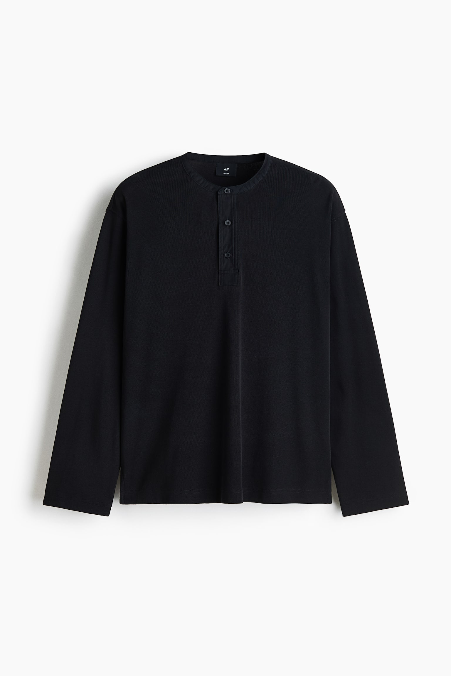 A black long-sleeve Henley shirt is shown facing front, featuring a round neckline with a short, three-button placket. The shirt is presented in a relaxed fit with dropped shoulders and straight, open-hemmed cuffs.