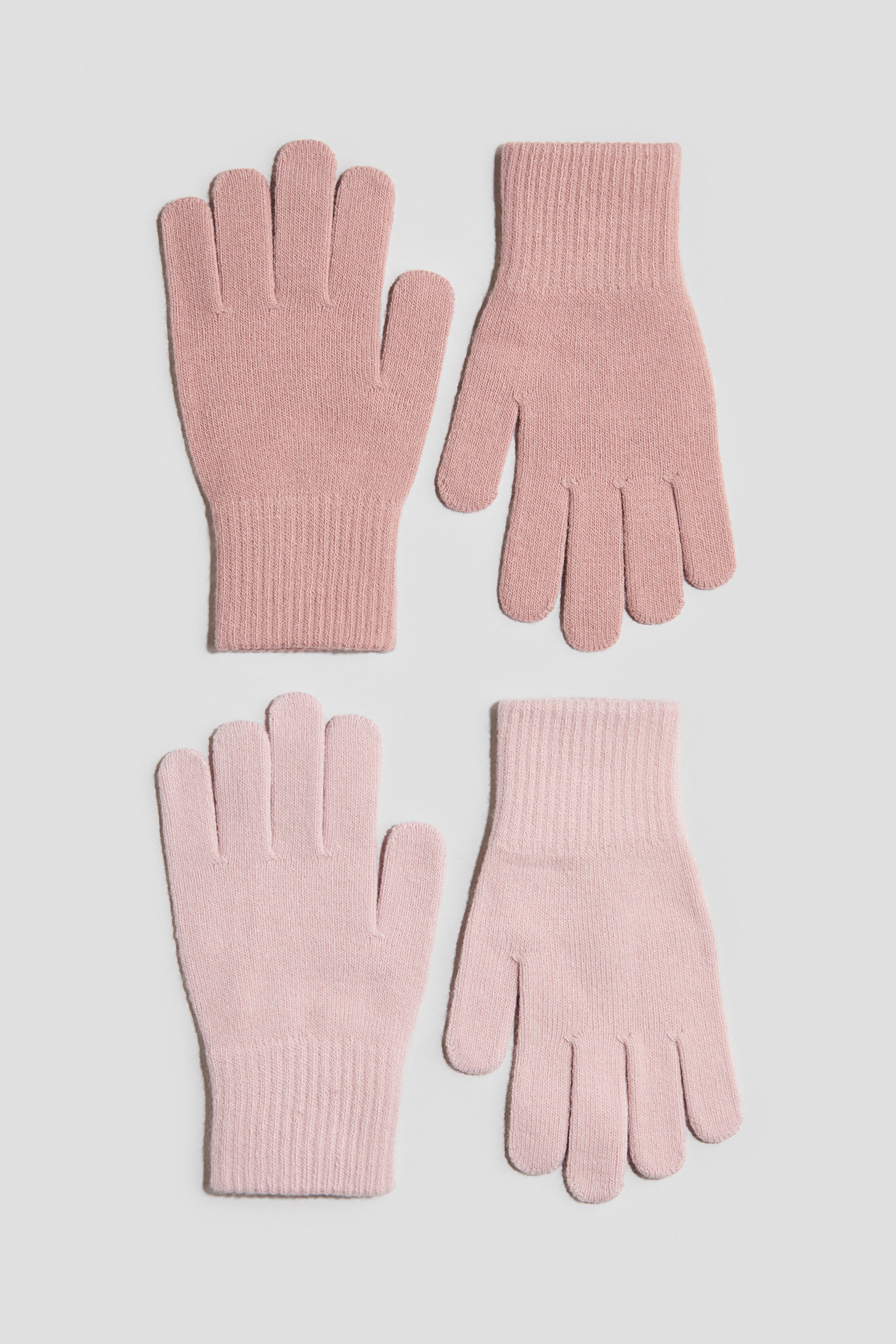 View larger image: Two pairs of gloves in a soft, fine knit are laid flat, facing forward, featuring one pair in dusty rose and another in light pink. Both pairs showcase a classic five-finger design with ribbed cuffs.
