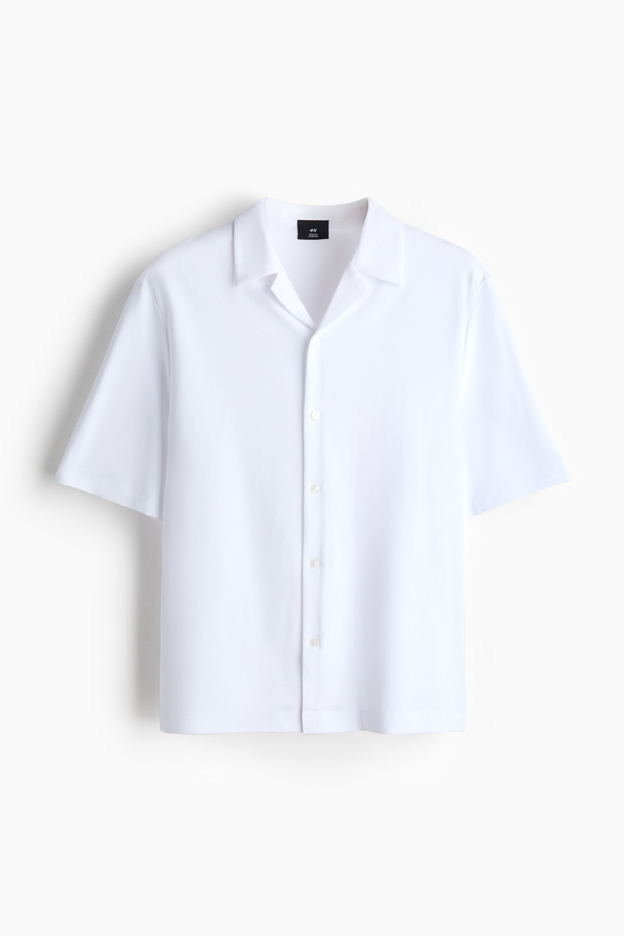 View larger image: A white short-sleeved shirt is shown from the front, featuring a camp collar, a full button-front closure with light-colored buttons, and a straight hem.