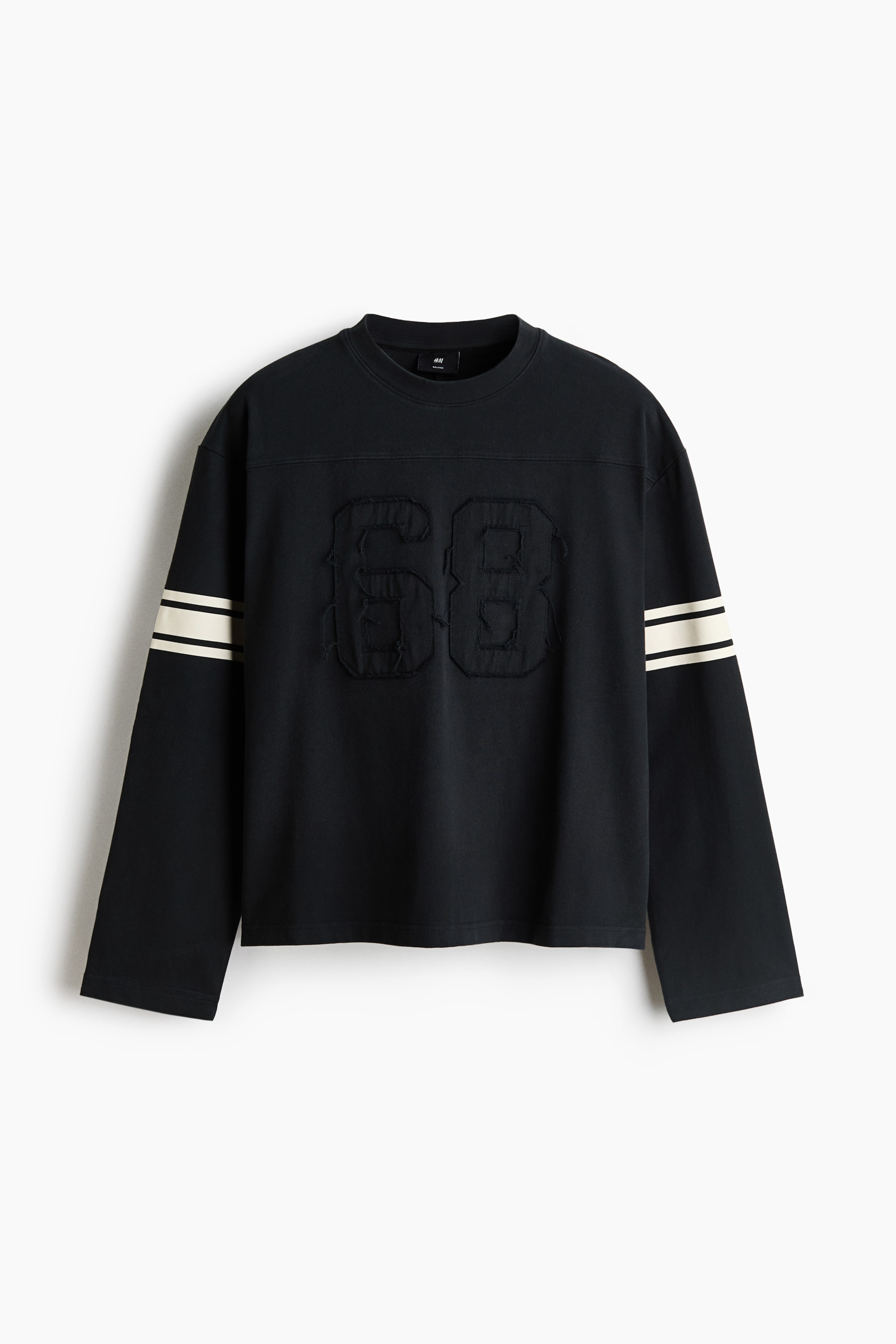 View larger image: A black long-sleeve crewneck top is shown from the front, featuring a tonal, frayed applique of the number "68" at the centre chest. The top is designed with dropped shoulders, a relaxed fit, and two contrasting off-white stripes wrapping around each upper sleeve.
