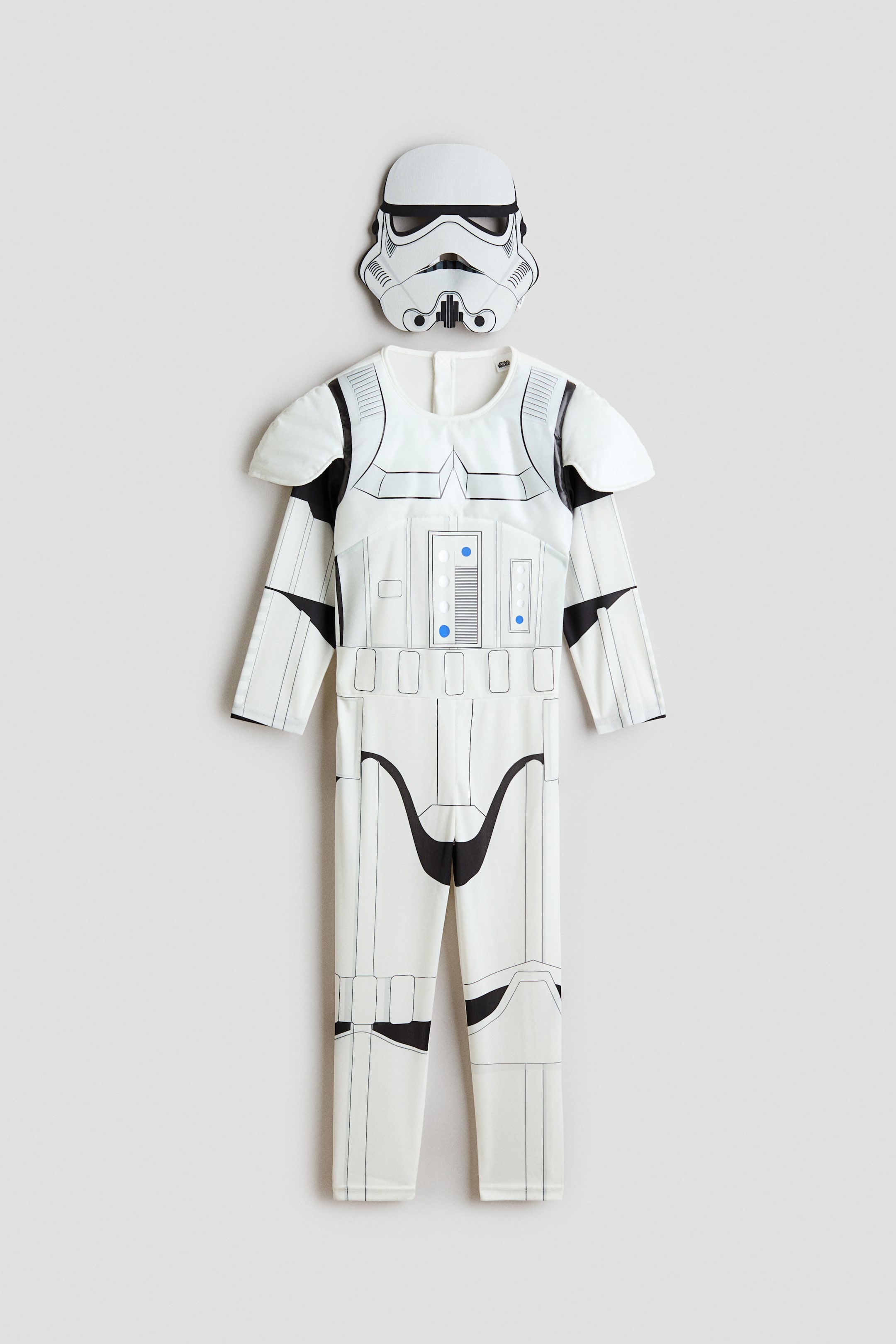 View larger image: A two-piece fancy dress costume is shown from the front, featuring a white jumpsuit with printed Stormtrooper armour details and a matching face mask. The long-sleeved jumpsuit features padded shoulder guards, a graphic control panel with blue accents, and black printed outlines representing armour plates, while the mask depicts the classic helmet design.