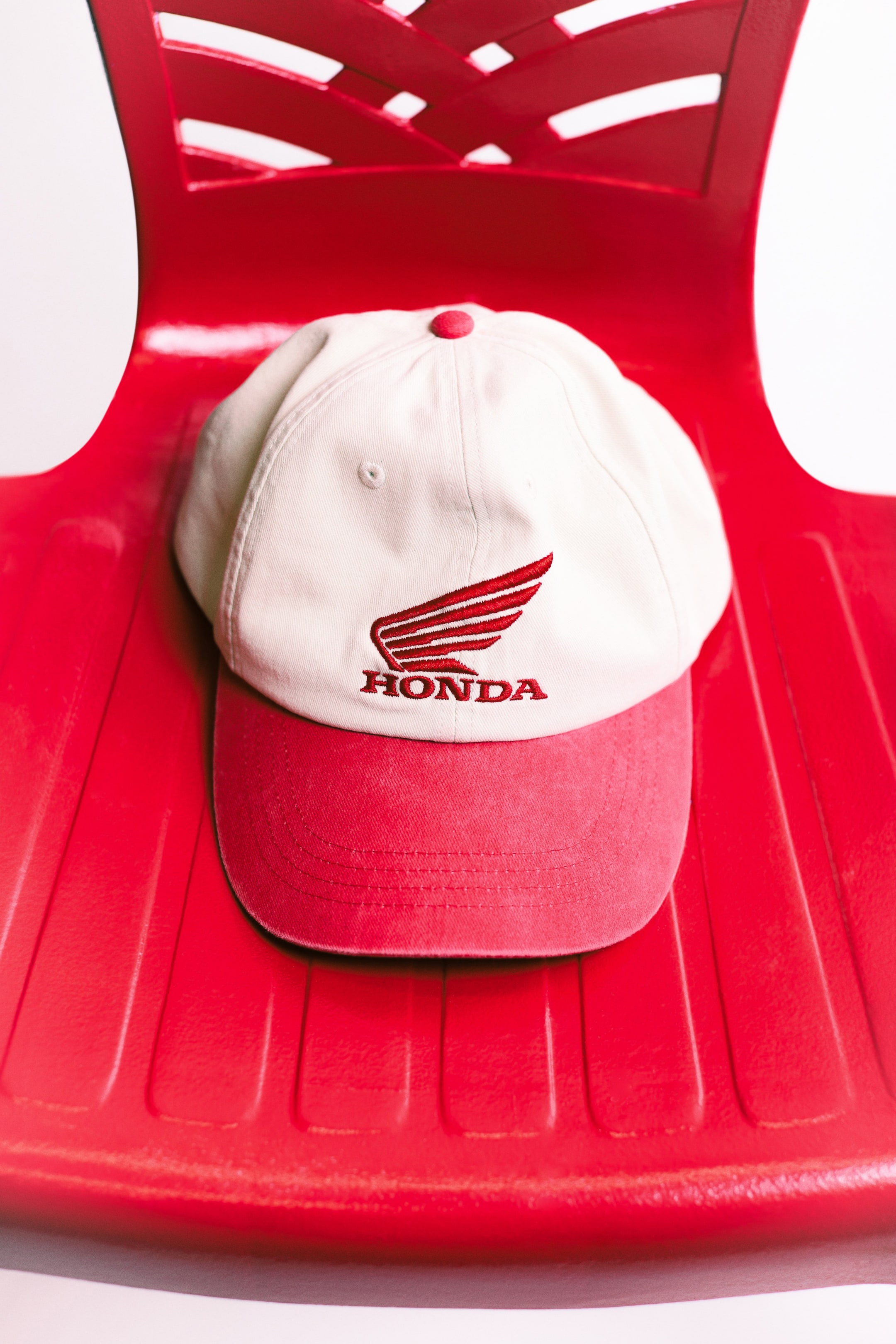 Ver imagen más grande: Una gorra de béisbol de color blanco roto presenta una visera roja, un botón superior rojo y un logo bordado de ala de Honda en rojo con el texto "HONDA" en el frente.