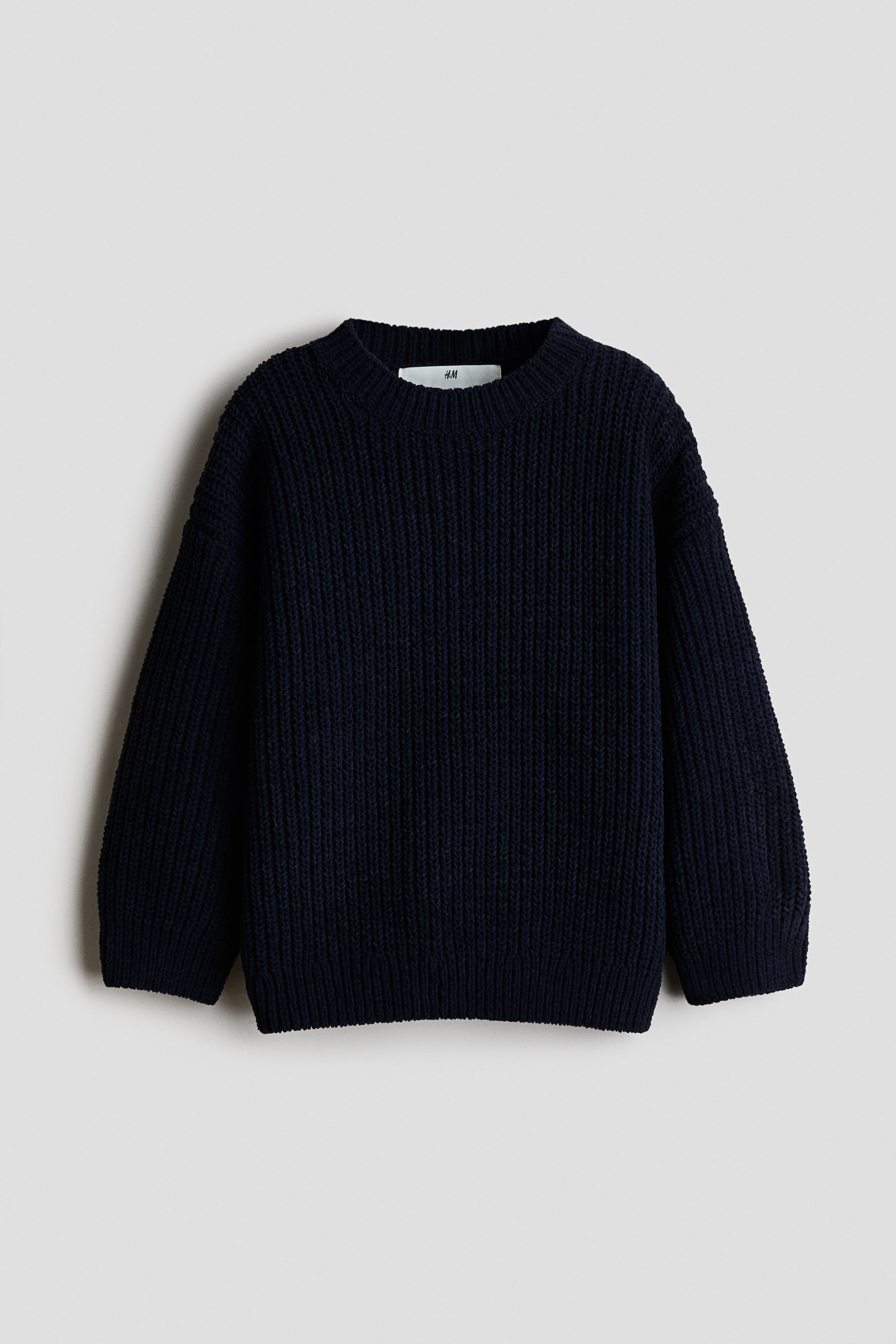 Ver imagen más grande: Un jersey de punto grueso azul oscuro con cuello redondo y mangas largas. Presenta puños y bajo acanalados, con una etiqueta blanca de la marca H&M visible en el interior del escote trasero.