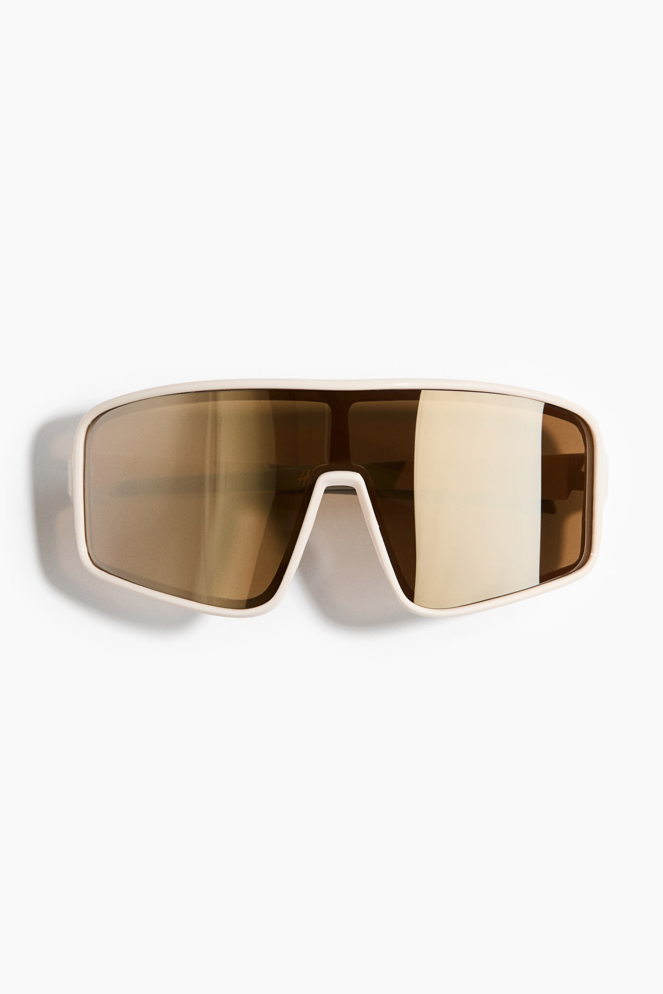 View larger image: Shield sunglasses feature white plastic frames and sidepieces, presenting a front view. The single, large plastic lenses are tinted gold, appearing reflective and offering UV protection.