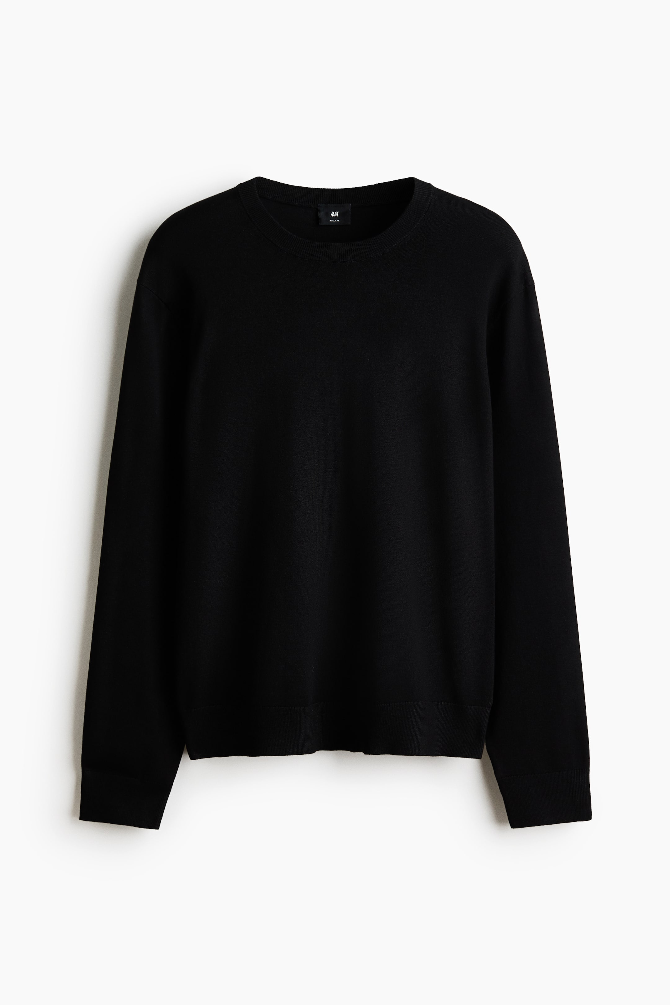 View larger image: A black, fine-knit sweater is facing front, showcasing a crew neck, long sleeves with ribbed cuffs, and a ribbed hem. A small black H&M Regular Fit label is visible at the back of the neck.