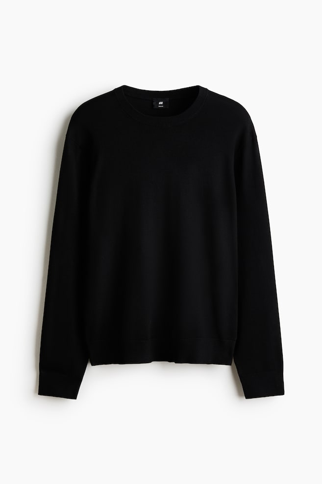A black, fine-knit sweater is facing front, featuring a crew neck, long sleeves with ribbed cuffs, and a ribbed hem. A small black H&M Regular Fit label is visible at the back of the neck. - 1