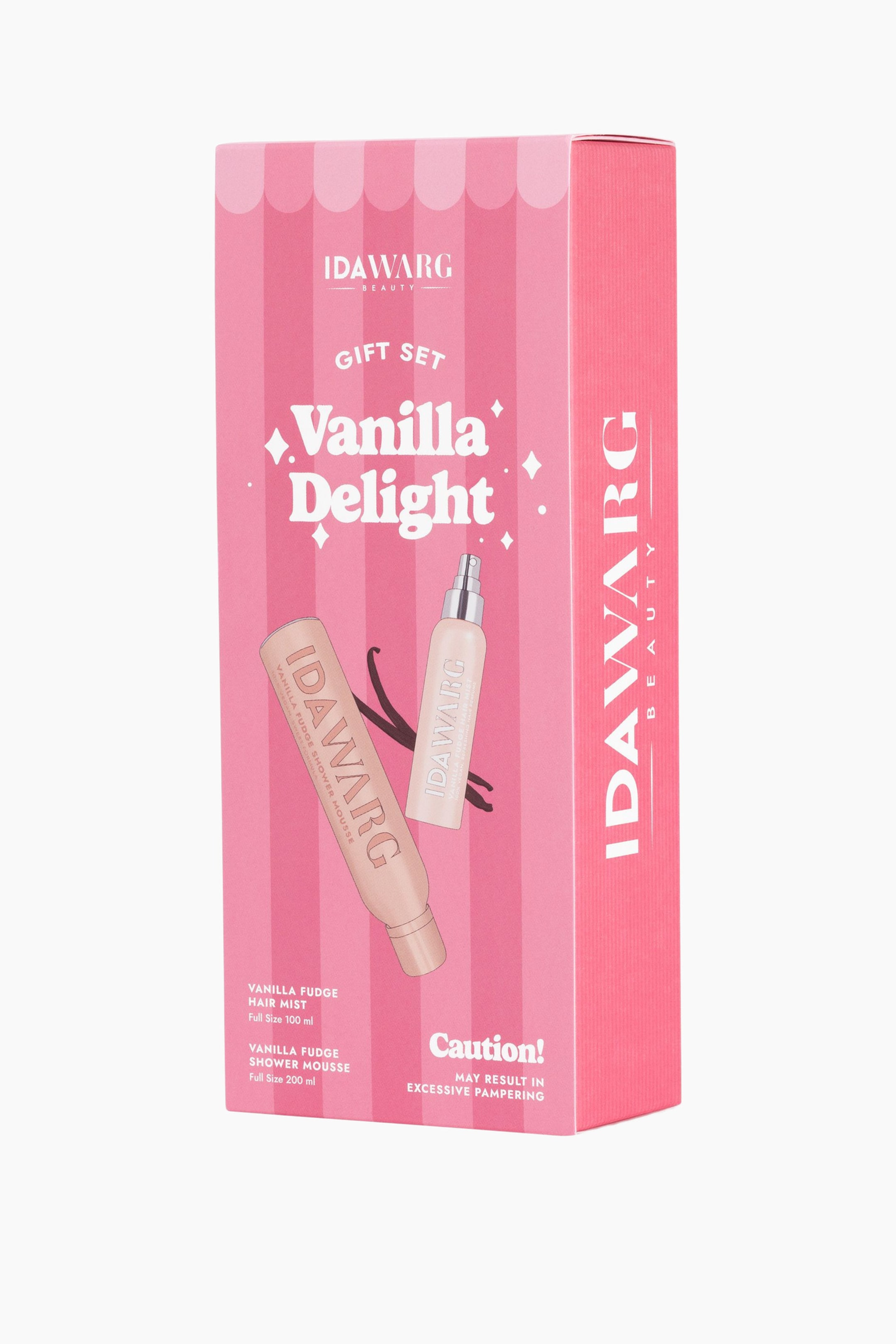 Se større billede: En rektangulær gaveæske vises fra fronten og højre side med et lodret candy-stribet mønster i pink og lysere pink på forsiden samt en ensfarvet mørkere pink på højre side. Frontpanelet viser brandingen "IDAWARG BEAUTY Vanilla Delight", illustrationer af en flaske med "Vanilla Fudge Hair Mist" og en flaske med "Vanilla Fudge Shower Mousse" samt deres tilhørende detaljer.
