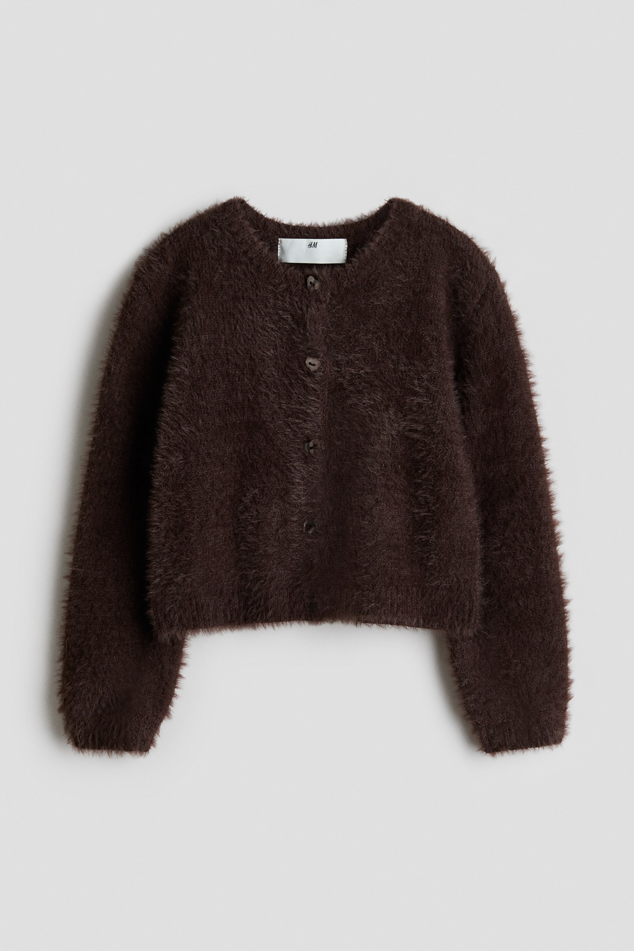 Agrandir l'image: Un cardigan moelleux marron foncé est présenté de face. Il est doté d'un col rond, de manches longues et d'une fermeture à boutons sur le devant avec cinq boutons foncés visibles.