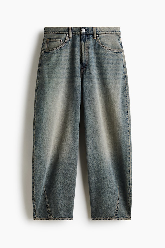 These five-pocket jeans in a faded blue denim wash are showcasing a baggy, barrel-leg silhouette from a front view, featuring a regular waist and a zip fly with a button. The legs are displaying a curved shape with fading on the thighs and stitched dart details at the inner hems. - 1