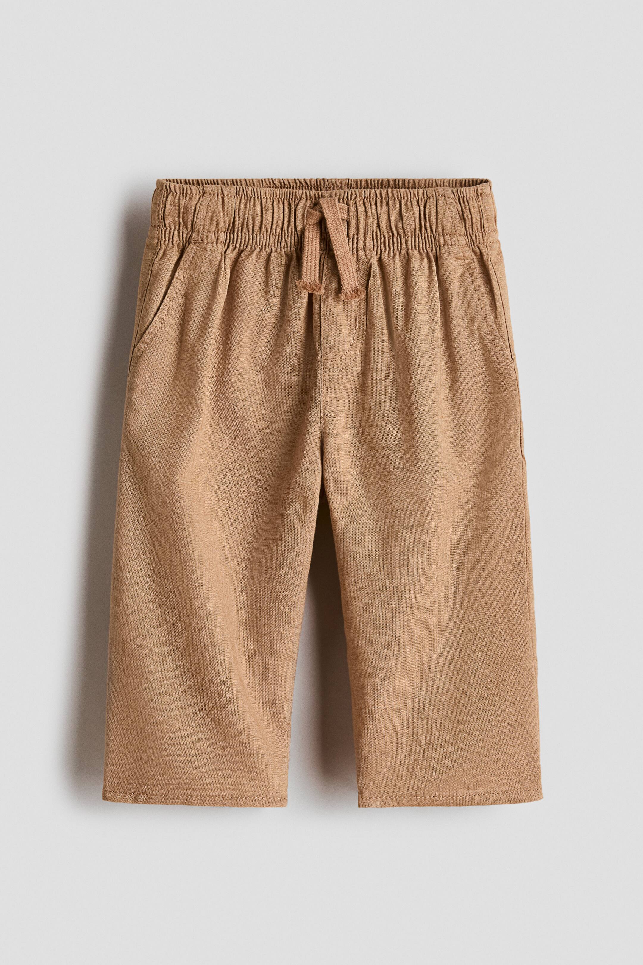 View larger image: A pair of tan pants is displaying from the front, featuring an elasticated drawstring waistband, two side-seam pockets, and straight legs with plain hems.