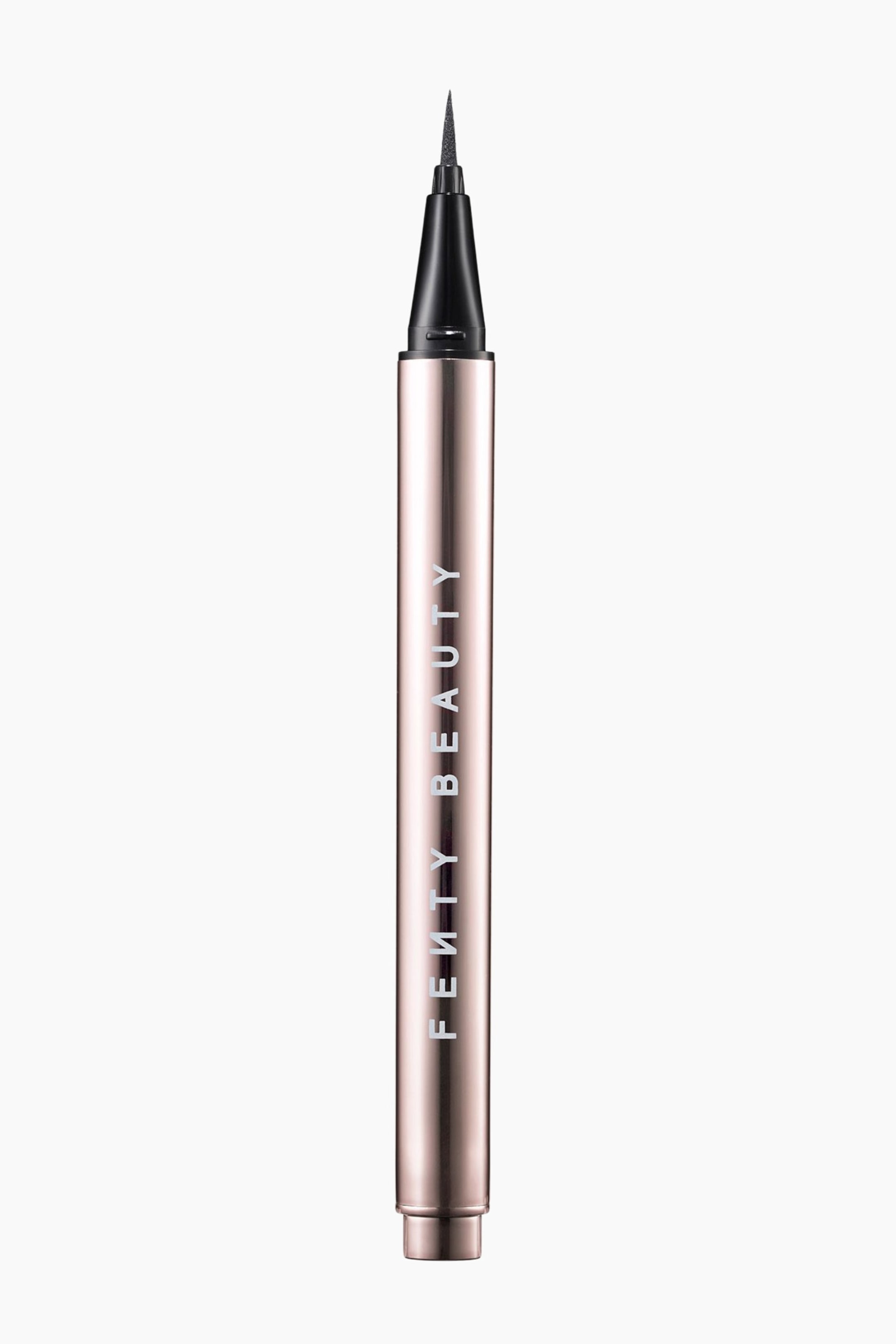 Visa större bild: Flyliner Longwear Liquid Eyeliner står upprätt och visar en metallisk roséguldkropp med varumärkesnamnet "FENTY BEAUTY" tryckt vertikalt. Den avlägsnade korken avslöjar en fin, spetsig applikator i svart filtspets som sträcker sig från en svart avsmalnande krage.