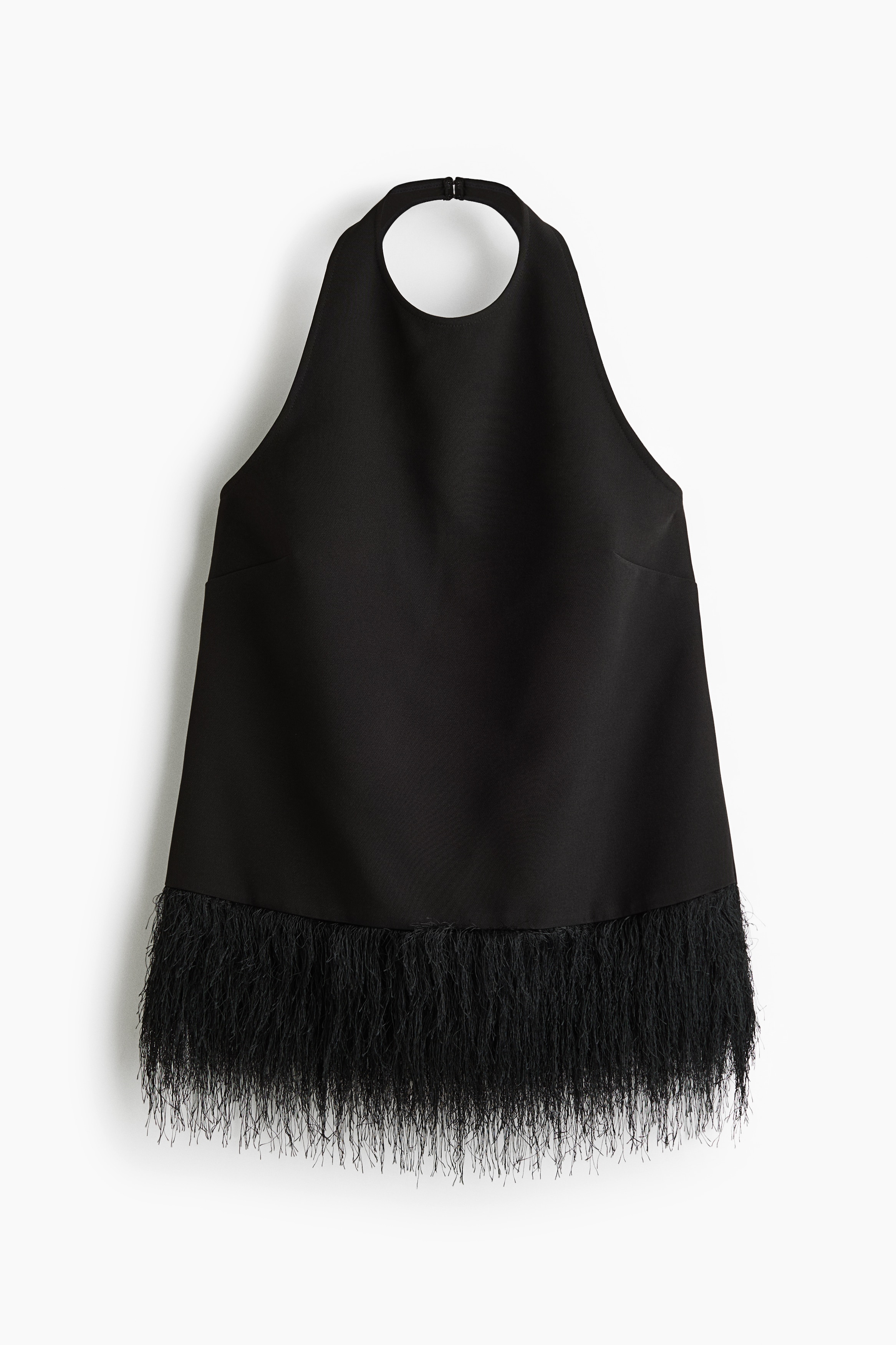 Černý halter top do A z tkané látky má na sobě modelka; je opatřen vysokým kulatým výstřihem a širokým texturovaným třásňovým lemem u spodního okraje. Top je zkombinován s černými koženými kalhotami, zatímco modelka pózuje.