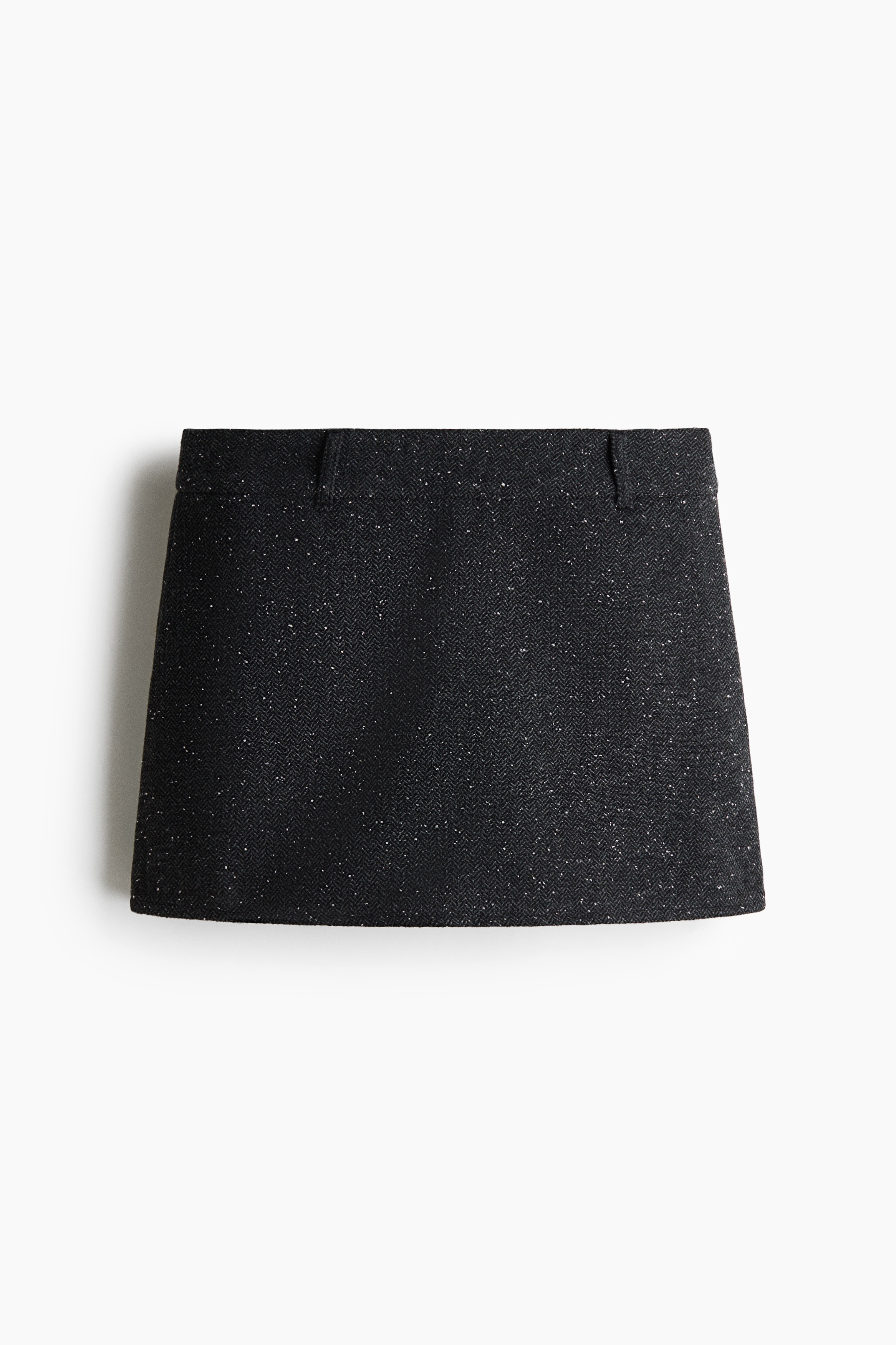 The model is wearing a matching dark grey speckled cropped jacket and mini skirt set. The jacket features a black contrast collar and front pockets, while the matching skirt is styled with a black leather belt over a white crop top.