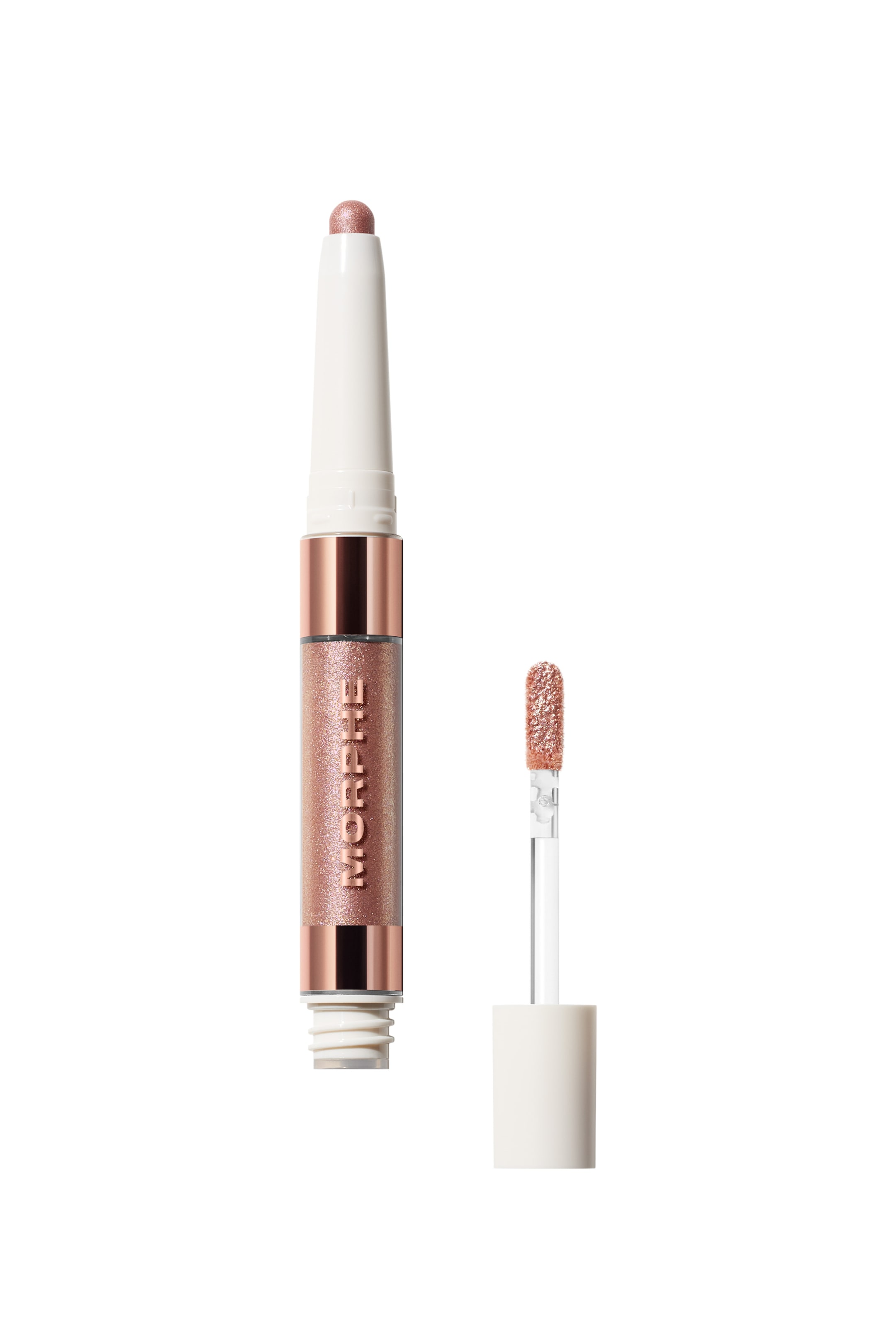 Visa större bild: En tvåsidig ögonskuggsprodukt står vertikalt, med en skimrande ros-kopparfärgad fast sticka med rundad spets i ena änden. Den andra änden är ett genomskinligt rör som innehåller en matchande skimrande flytande produkt, med "MORPHE" vertikalt och dekorerad med roséguldband och vit hölje, med en separat paddelformad applikatorstav, täckt i samma skimrande produkt, placerad till höger.