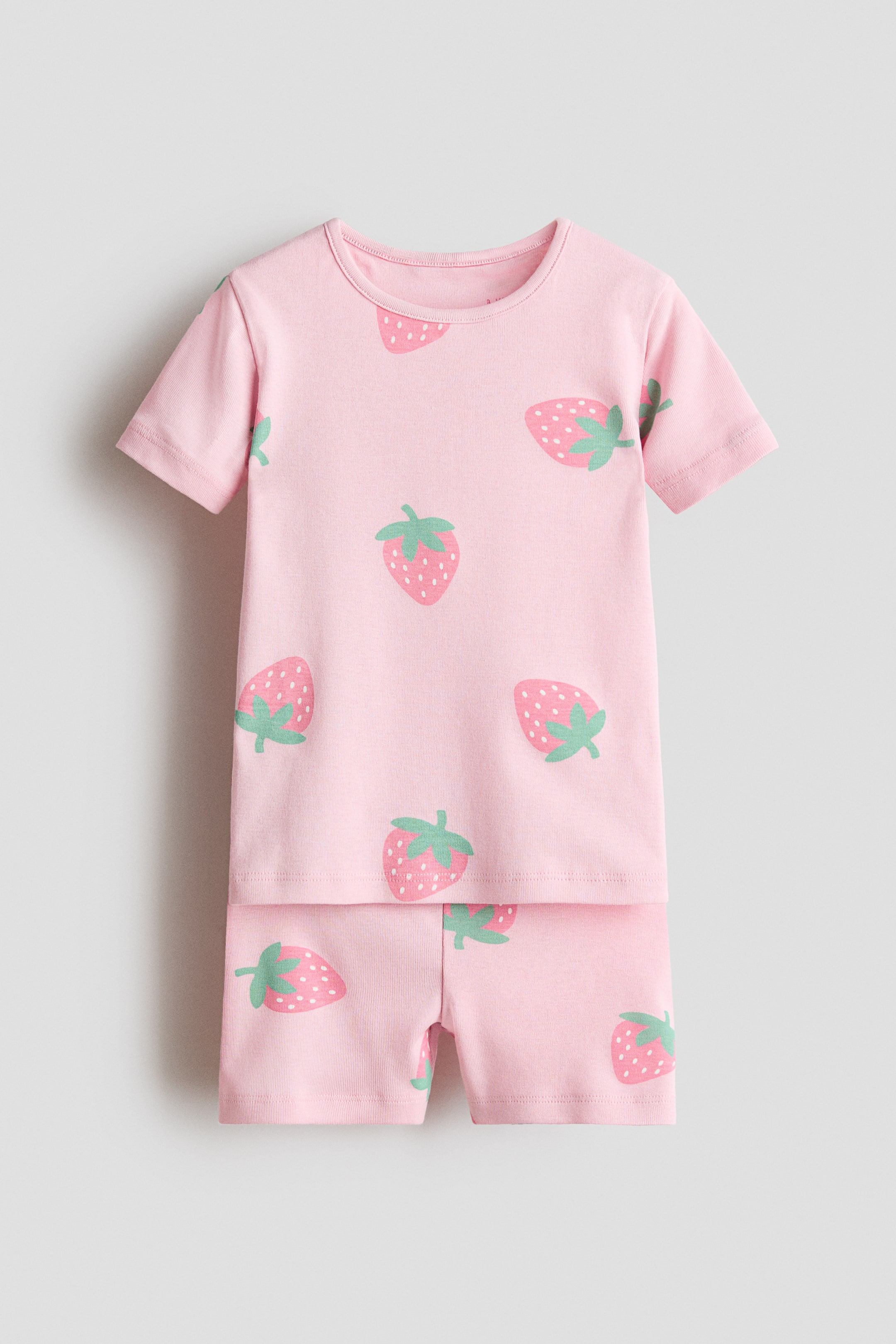 View larger image: Pyjamas showcase a pink short-sleeved T-shirt paired with matching shorts, both displayed from the front and featuring an all-over strawberry print. The T-shirt is crafted with a round, narrow-trimmed neckline, and the shorts include an elasticized waist.