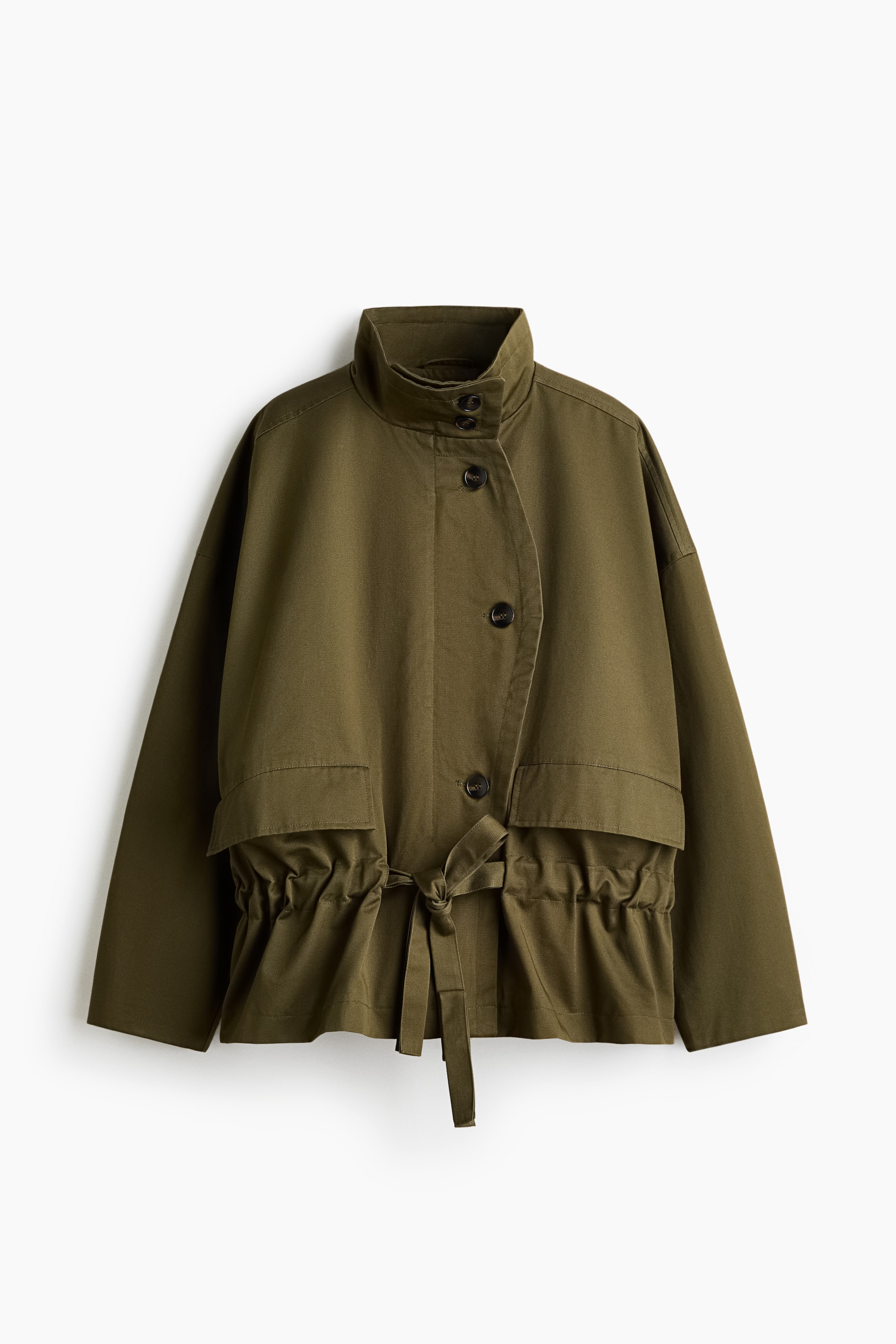 Nagyobb kép megtekintése: Az olívazöld dzseki magas, felálló gallérral és részleges, gombos elülső záródással, átfedő panellel rendelkezik. Elöl alul fedőlapos zsebekkel és derékban húzózsinóros, megkötős részlettel is rendelkezik, amely összehúzott, karcsúsító hatást kelt.
