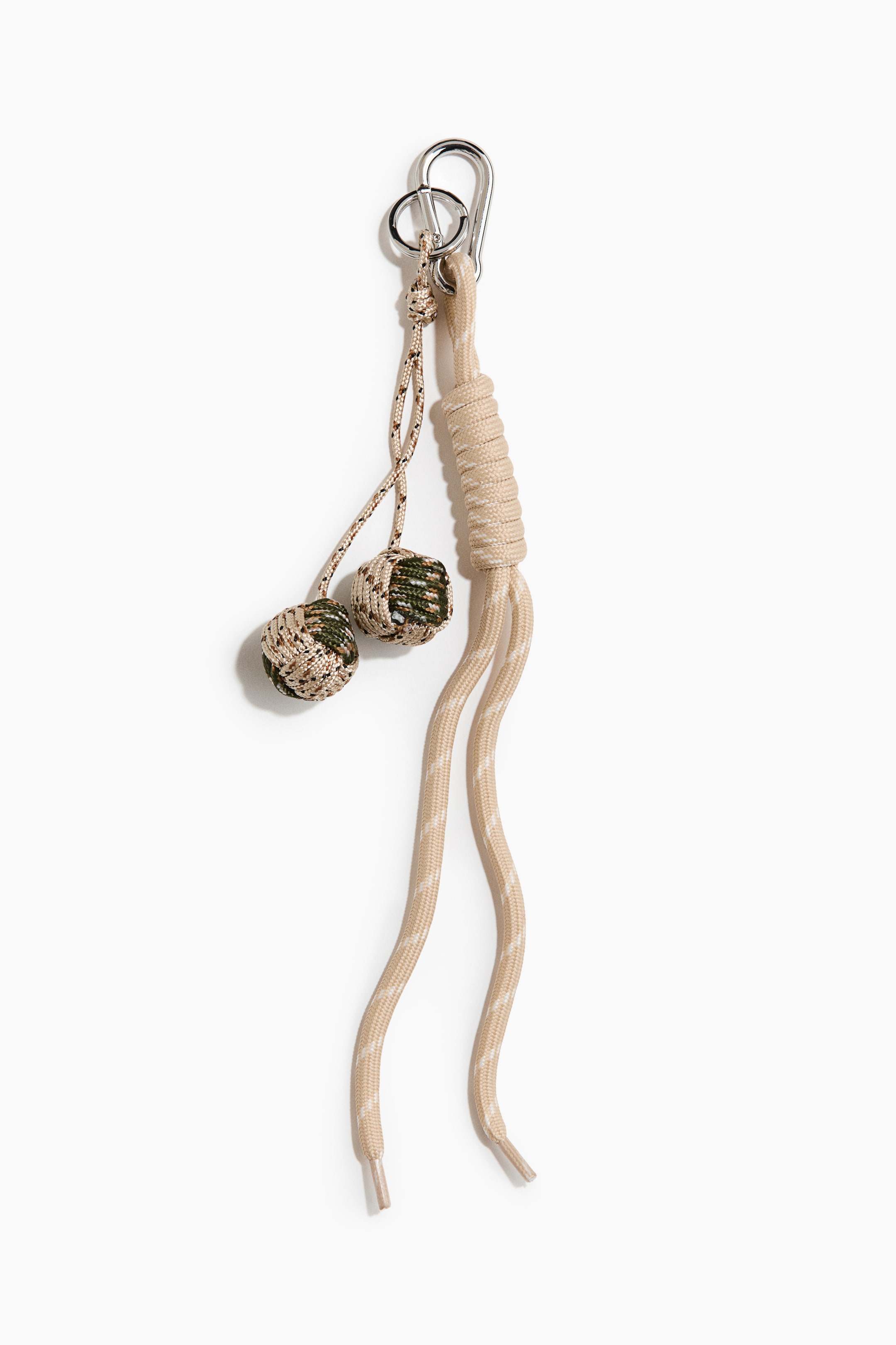 Ingrandisci l'immagine: Un charm per borsa presenta un moschettone argentato e un anello diviso nella parte superiore, con un corpo principale di corda beige chiaro. Una sezione della corda è strettamente avvolta, e due decorazioni sferiche avvolte in corda con motivo mimetico pendono dall'anello diviso.
