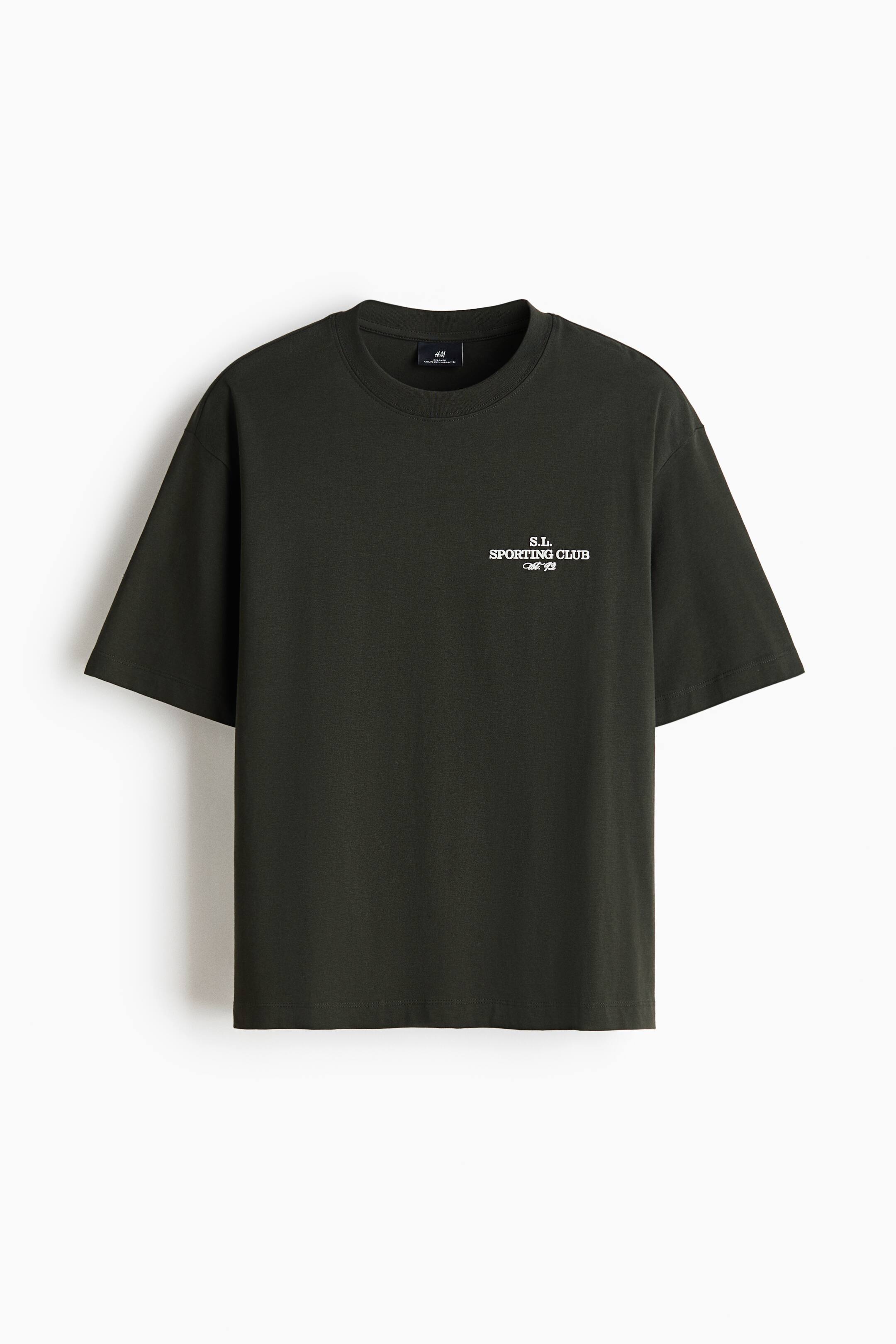 View larger image: A dark green, oversized crew-neck T-shirt is shown front-facing, featuring wide short sleeves and a straight hem. A small white graphic text reading "S.L. SPORTING CLUB" is printed on the left chest.