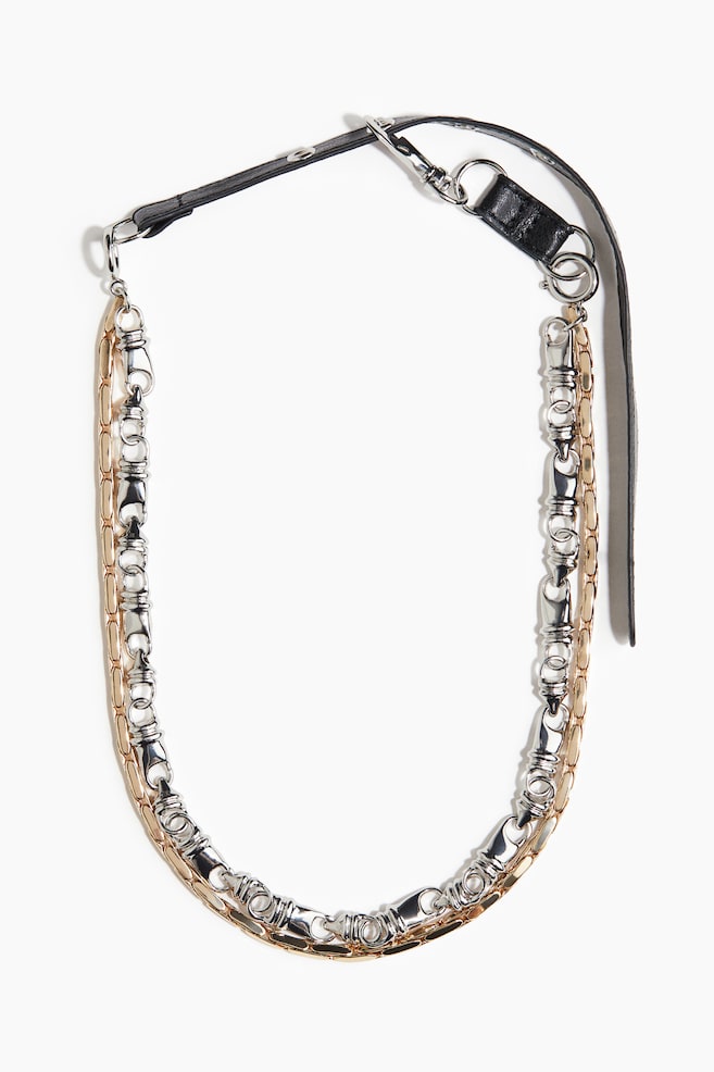 A two-strand necklace is featuring a gold-toned flat-link chain and a silver-toned chain with alternating cylindrical and ring links. Both chains are connecting to a black coated fabric strap at the back, which is adjustable with a lobster clasp. - 1