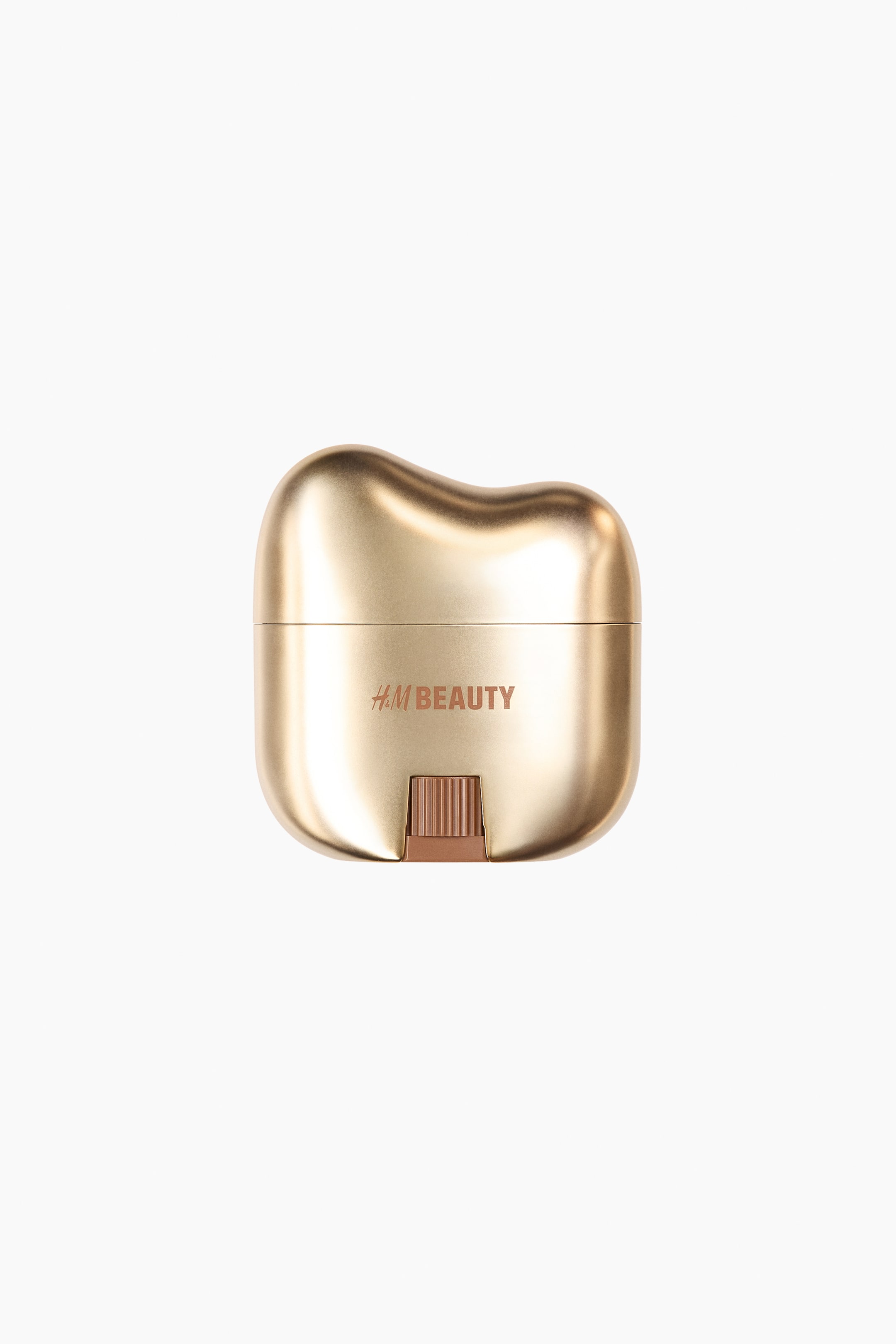 View larger image: A gold-toned cosmetic product faces forward, featuring a smooth, metallic casing with an irregularly rounded top contour. The text "H&M BEAUTY" appears on the front, positioned above a small, ribbed, bronze-colored slider.