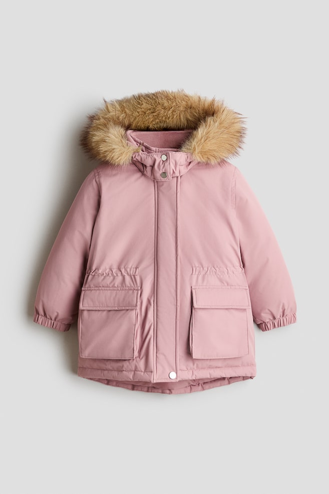 Ein winterlicher Parka in staubigem Rosa ist frontal ausgerichtet und zeigt eine Kapuze mit flauschigem Kunstfellbesatz sowie einen verdeckten Frontverschluss mit Druckknopfdetails. Die Jacke verfÃ¼gt Ã¼ber elastische ÃrmelbÃ¼ndchen, einen leicht geschwungenen Saum und zwei groÃe aufgesetzte Pattentaschen vorne mit gerafften Elastikdetails. - 1