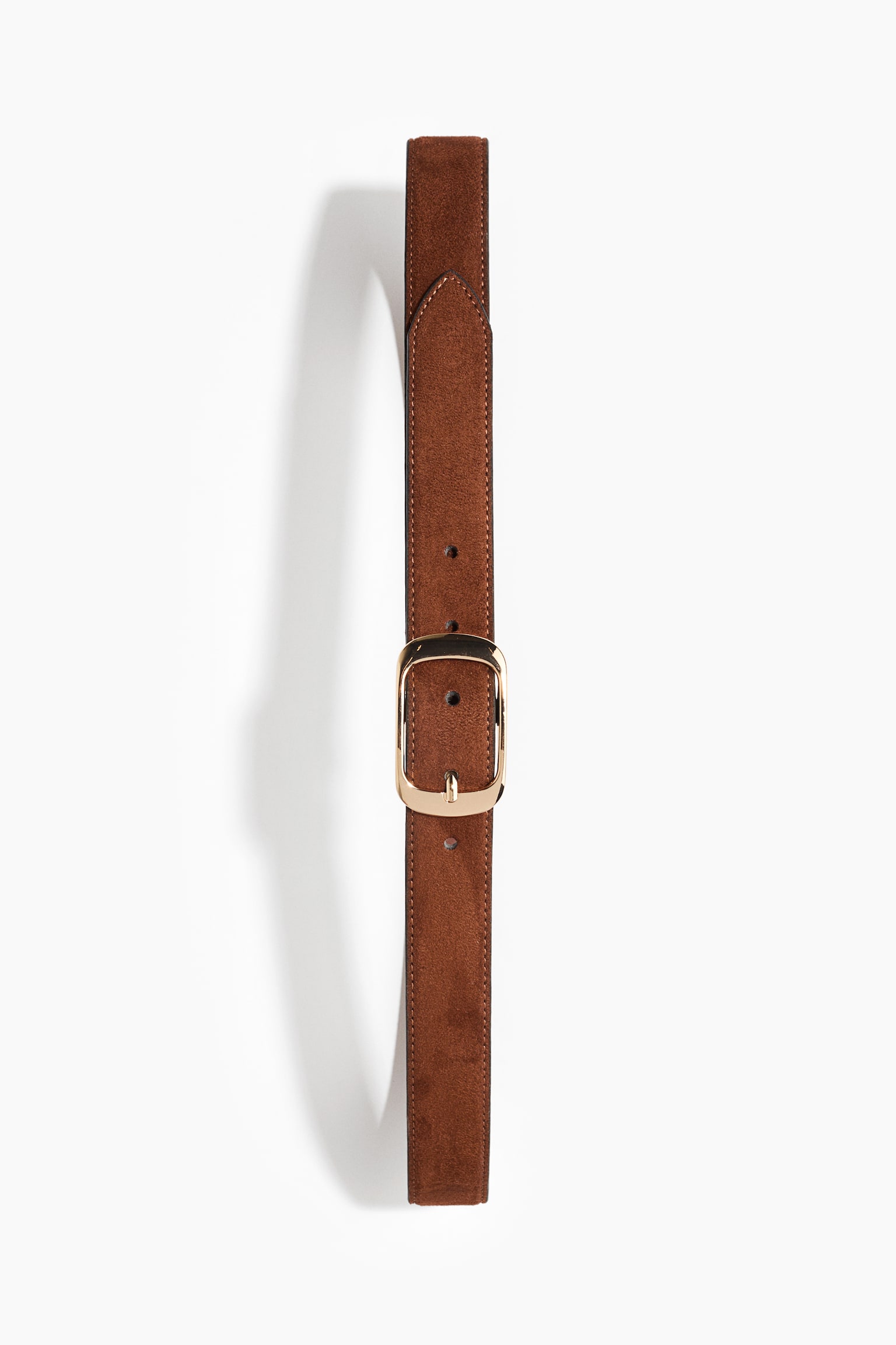 A brown suede belt is shown front-on, extending vertically, featuring a polished gold-toned metal buckle with rounded corners. The belt displays tonal topstitching along its edges and is fastened with its pointed tip directed upwards.