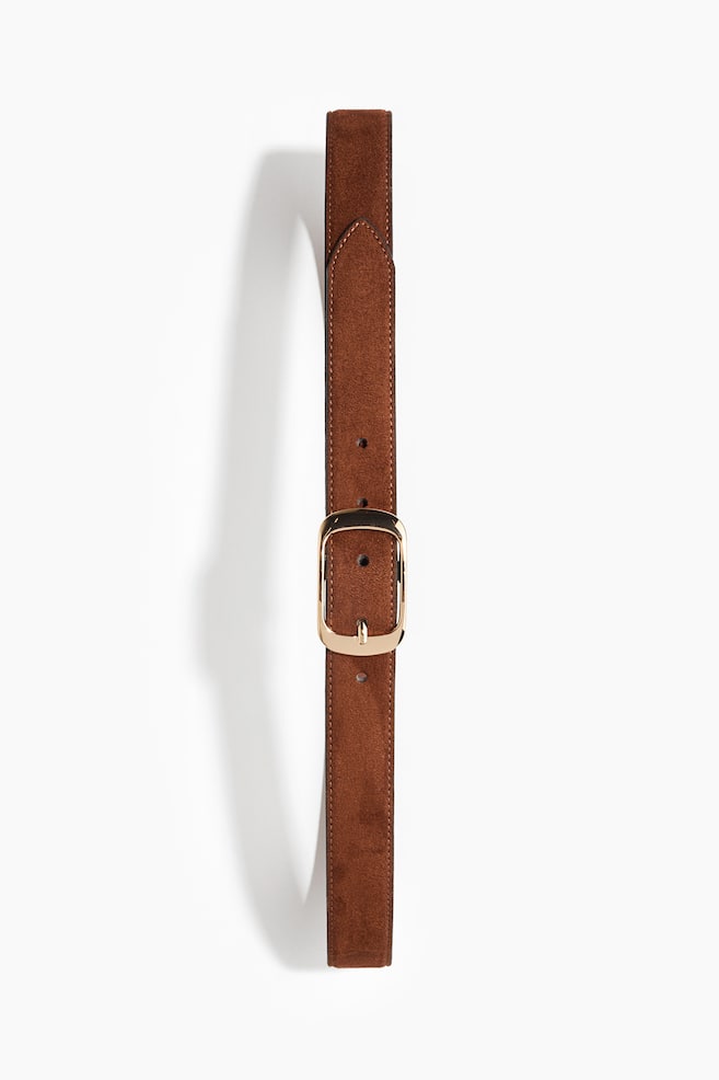 A brown suede belt is shown front-on, extending vertically, featuring a polished gold-toned metal buckle with rounded corners. The belt displays tonal topstitching along its edges and is fastened with its pointed tip directed upwards. - 1