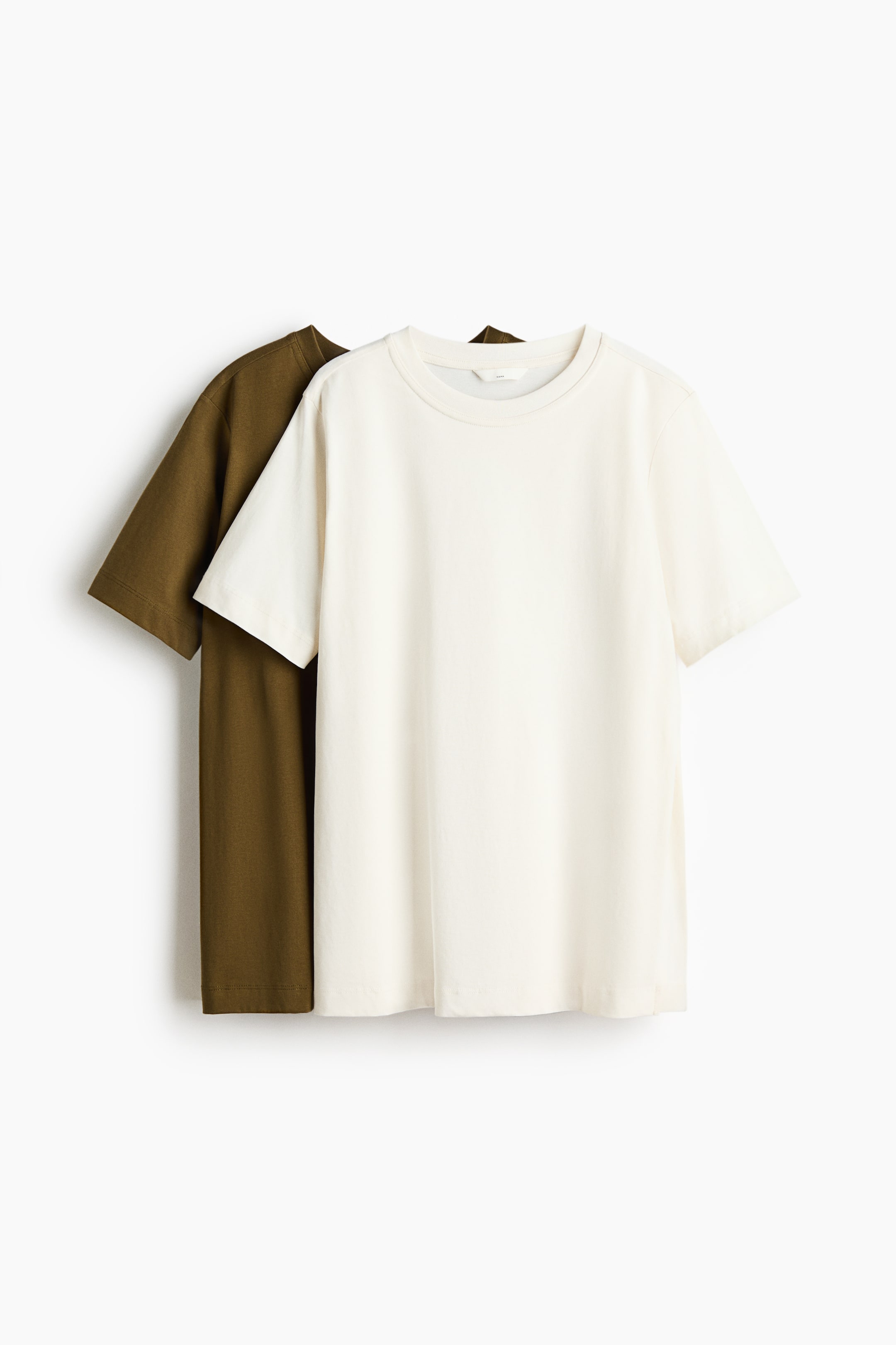View larger image: Two soft jersey T-shirts are showcasing their fronts. The off-white shirt in the foreground features a classic T-shirt style with a round neckline and dropped shoulders. A dark olive green shirt is partially visible behind it.