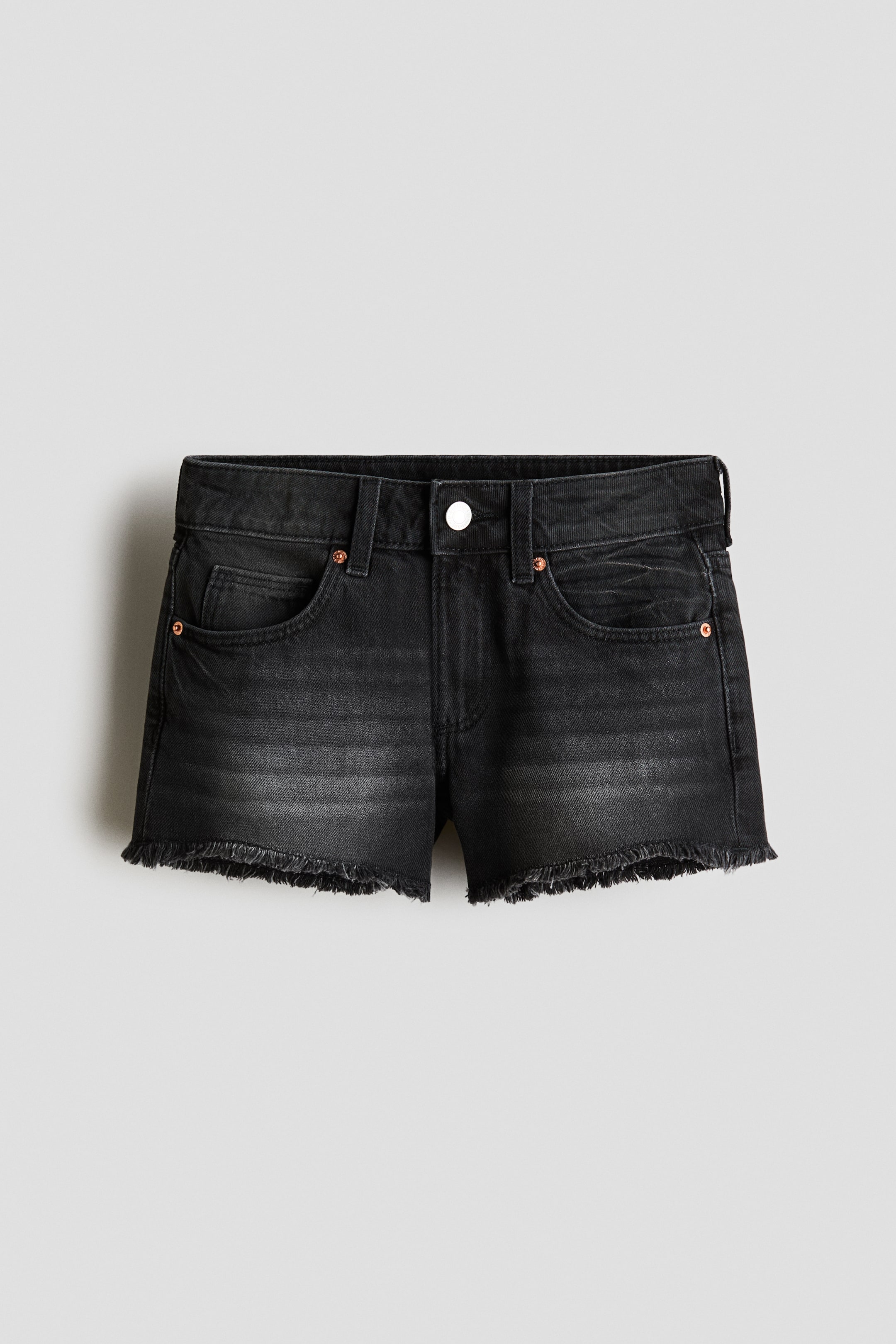 View larger image: Black denim shorts shown from the front, featuring a faded wash and a frayed hem. They are designed with a waistband, belt loops, a single-button closure, and front scoop pockets with visible rivets.