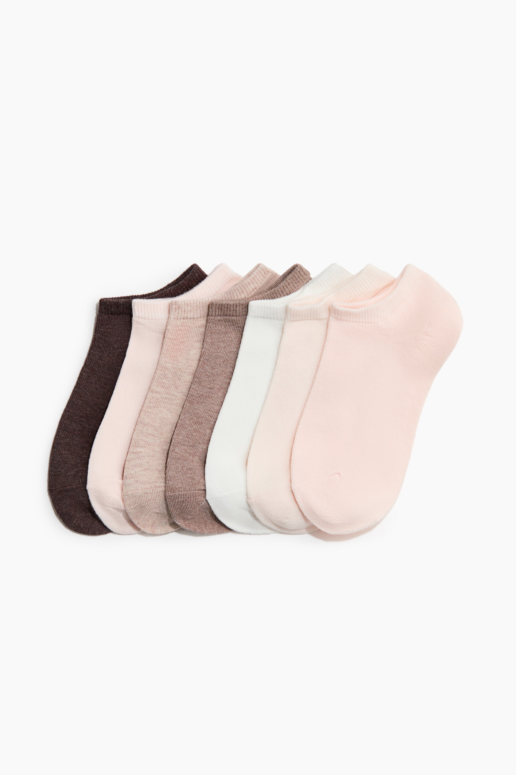 View larger image: Fine-knit trainer socks in a soft cotton blend are arranged in a row. Seven pairs are displaying a gradient of colors, ranging from dark brown to light pink, with each sock featuring a low-cut front opening.
