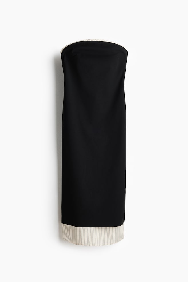 Se muestra de frente un vestido bandeau ajustado, hasta media pantorrilla, en tela tejida negra, con diseÃ±o de capas. Una capa inferior color blanco hueso, con finas rayas, se extiende ligeramente por encima del escote sin tirantes y notablemente por debajo del dobladillo. - 1