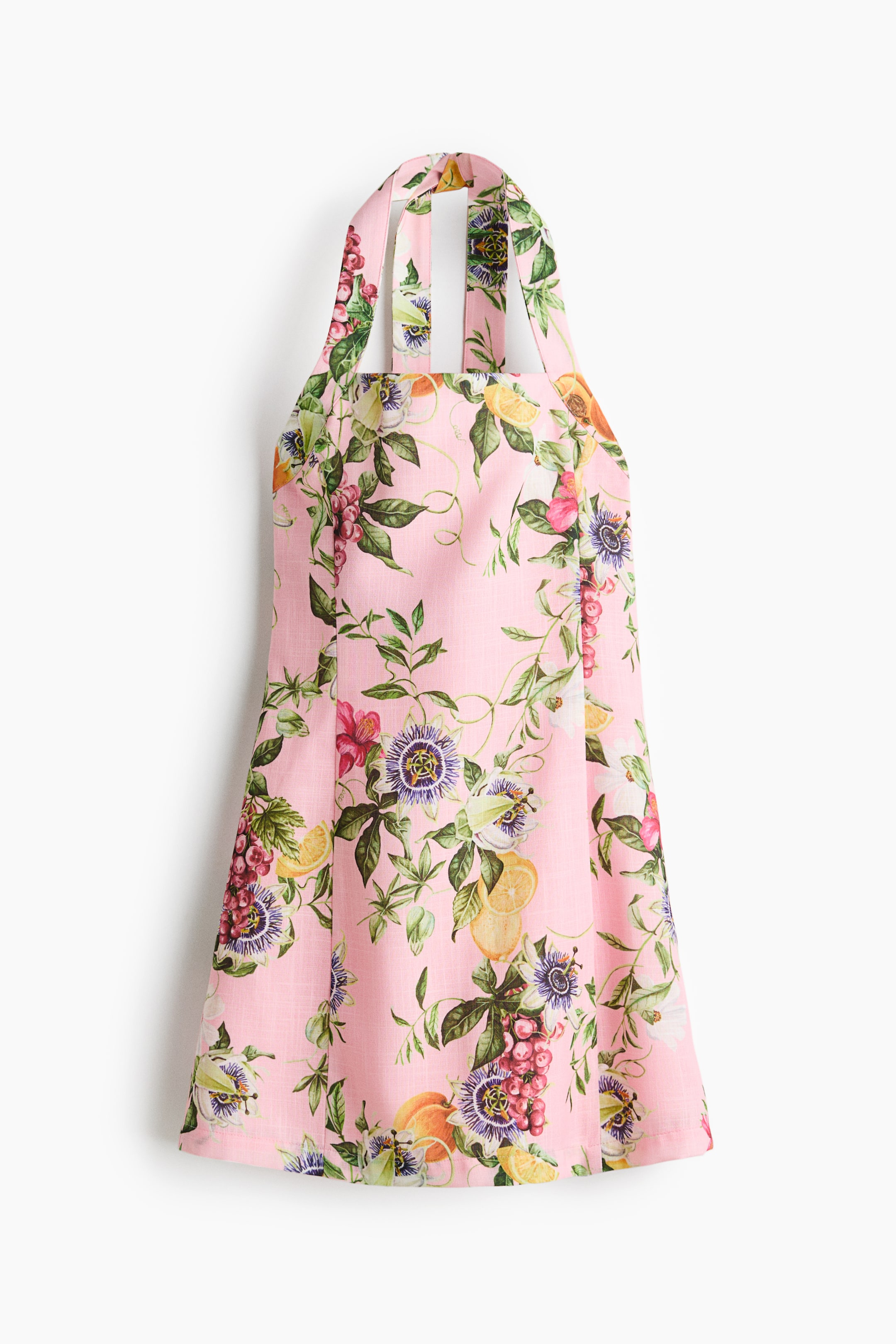 View larger image: This pink apron showcases a lively floral and fruit pattern, featuring passion flowers, grapes, and citrus slices. The apron includes wide straps that create a halter-neck design, with its main body gently flaring towards the hem.