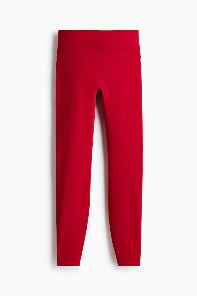 Red leggings are presenting FRONT, featuring a wide, high waistband and tapering, form-fitting legs. - 1