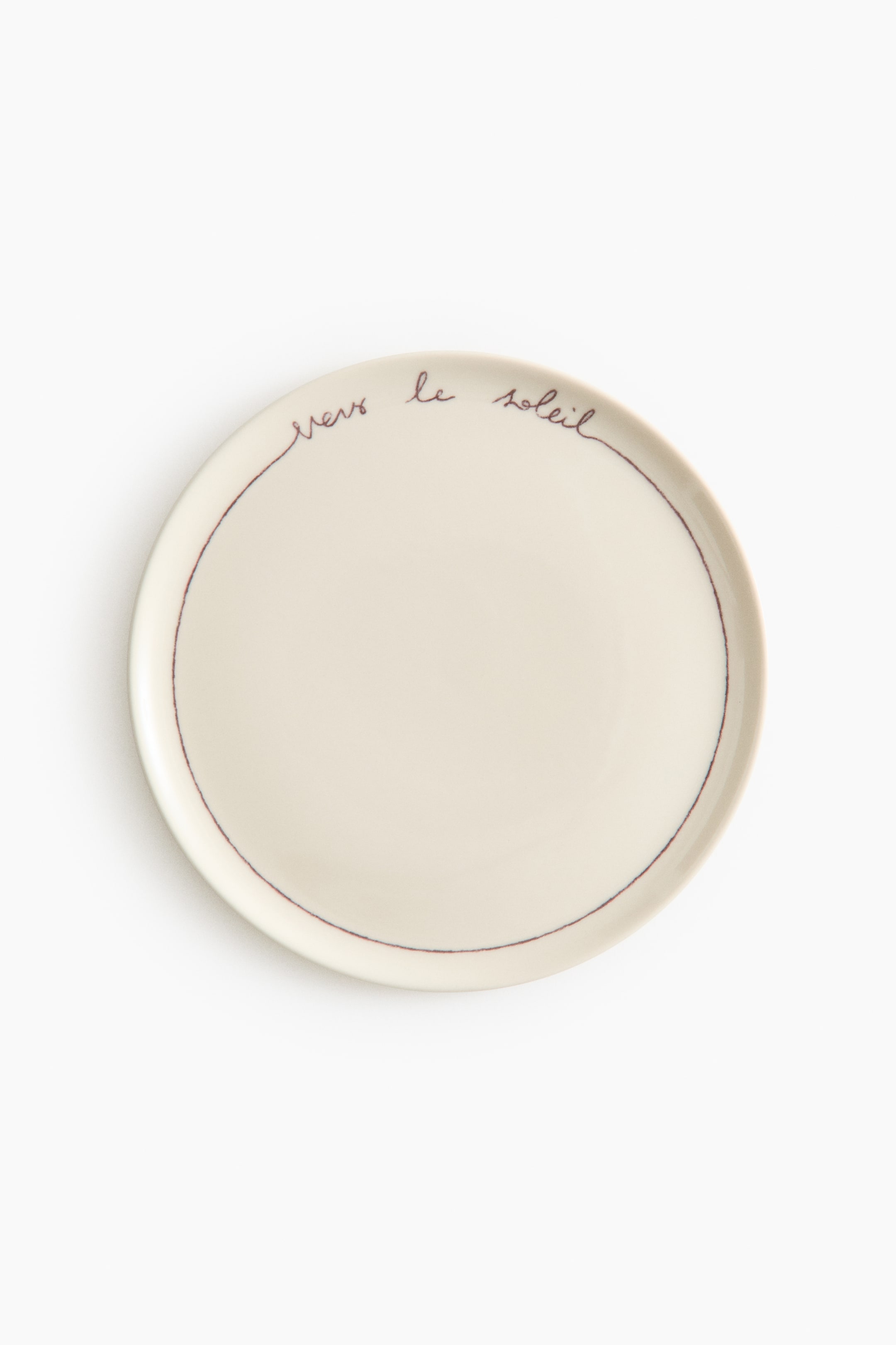 Voir une image plus grande: Un assiette ronde de couleur crème présente sa surface supérieure. Une fine ligne rouge foncé encercle le bord intérieur, et la phrase manuscrite "vers le soleil" apparaît dans la même couleur rouge foncé près du bord supérieur.