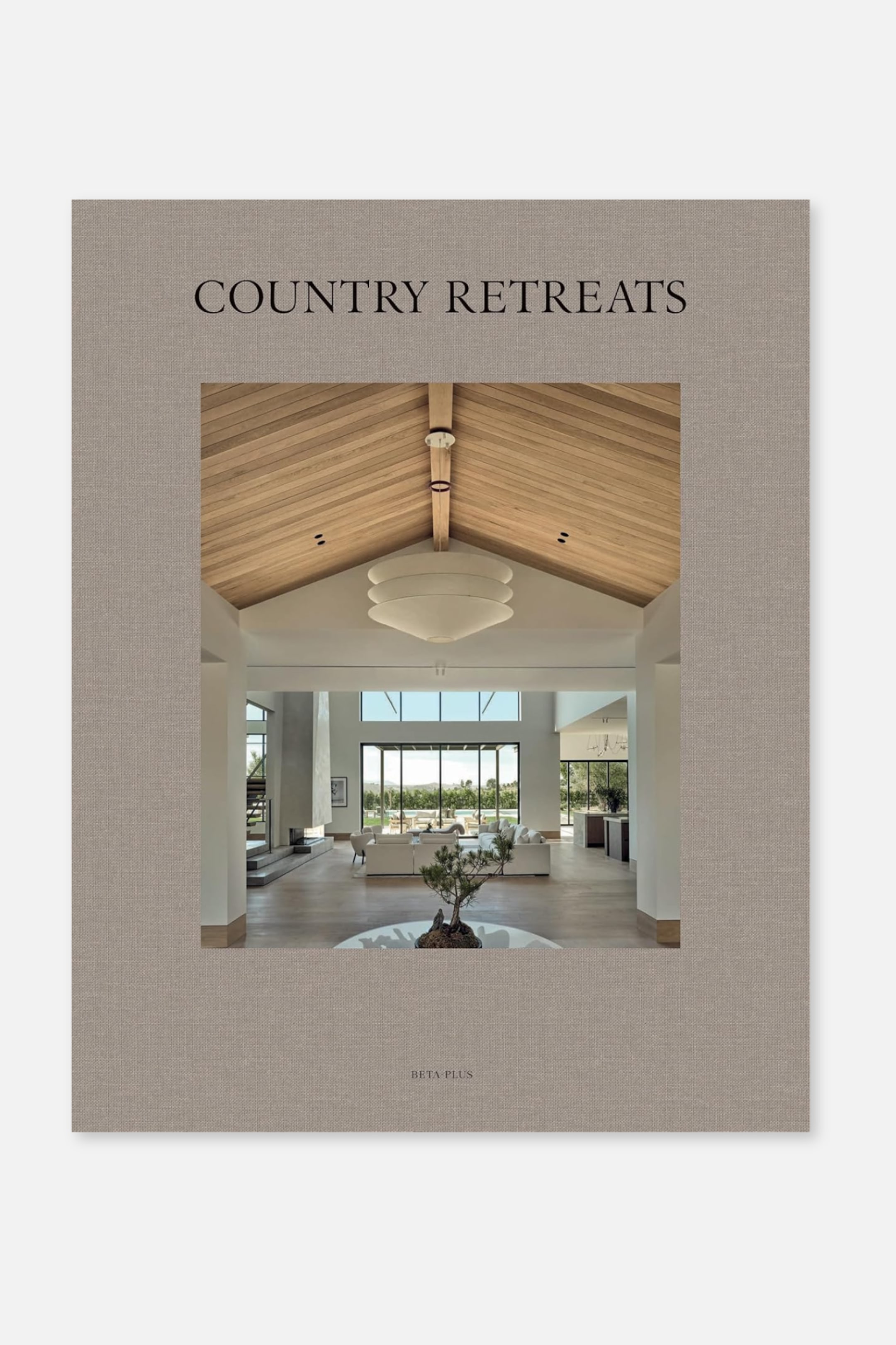 Grotere afbeelding bekijken: Een hardcover boek getiteld 'COUNTRY RETREATS' toont zijn voorkant. De omslag is van beige, gestructureerd materiaal, met de titel in zwarte schreefletter, een grote afbeelding van een eigentijds interieur met een houten plafond, en 'BETA PLUS' onderaan gedrukt.