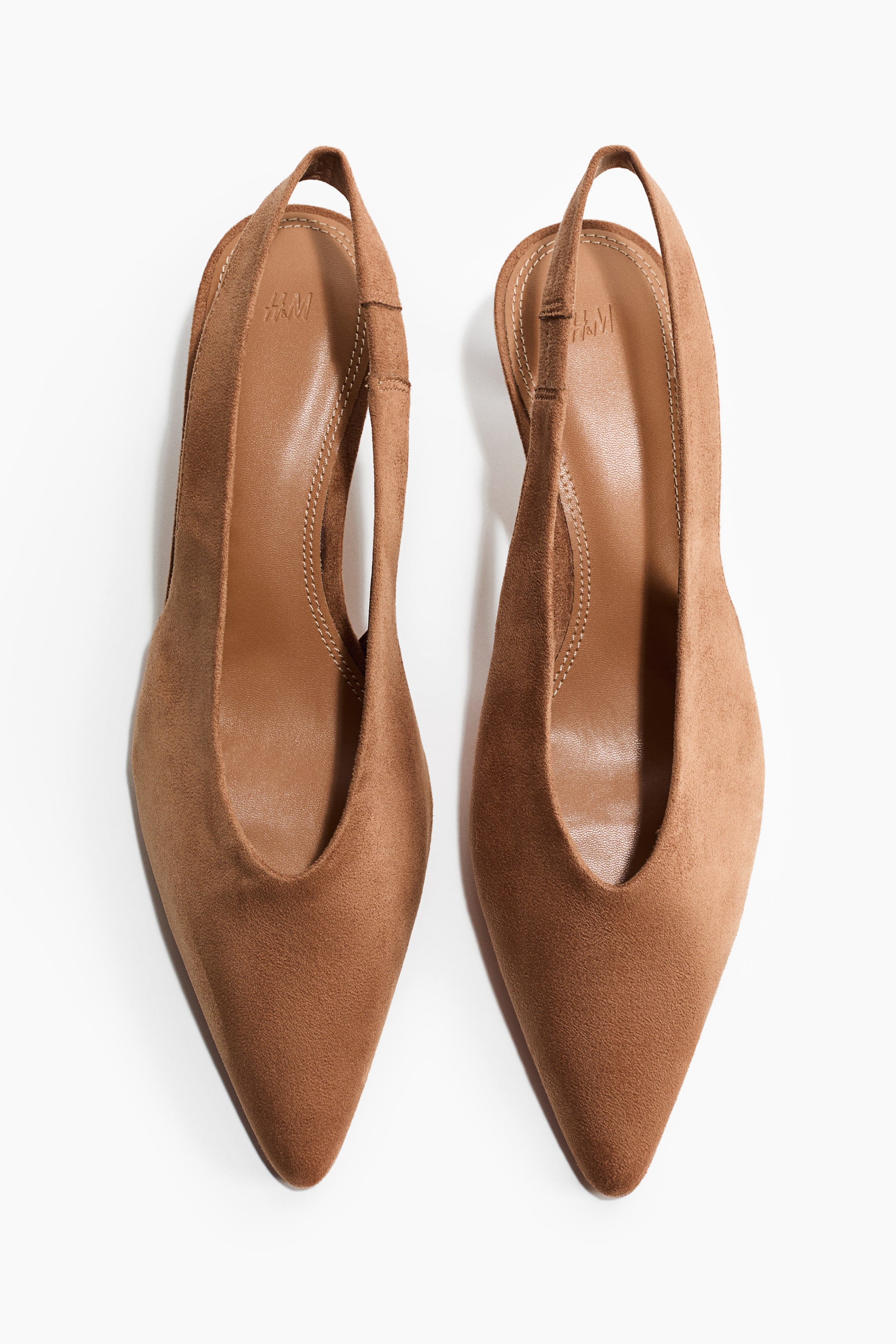 View larger image: A pair of brown slingback heels featuring pointed toes, d’Orsay-style cut-out sides and elastic slingback straps, all in a suede-like finish, completed with light brown insoles with visible stitching.