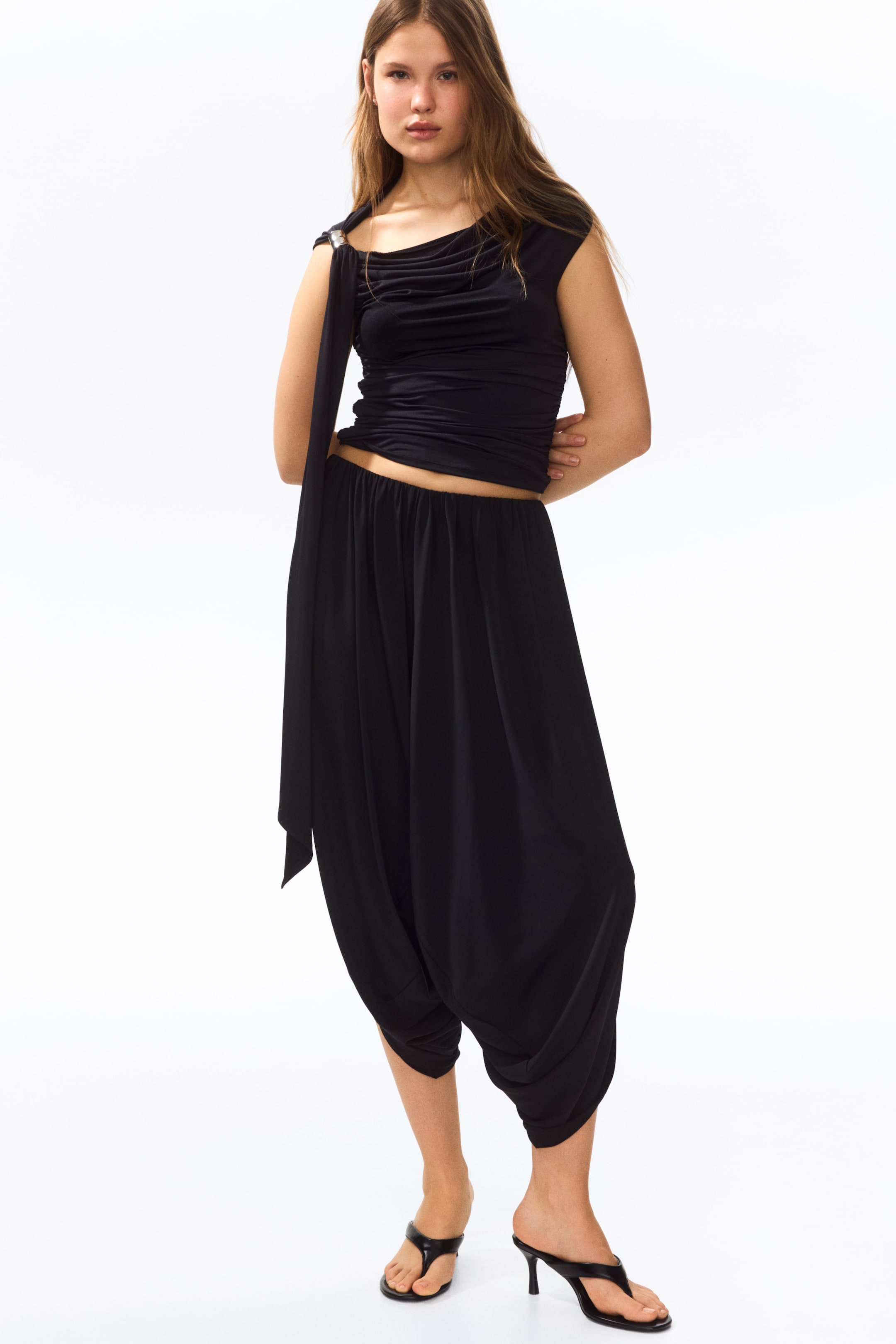 Grotere afbeelding bekijken: 3/4-lengte, loszittende broek in stretch jersey met een elastische taille, ballonpijpen en overslagzijden worden gedragen door het model.
