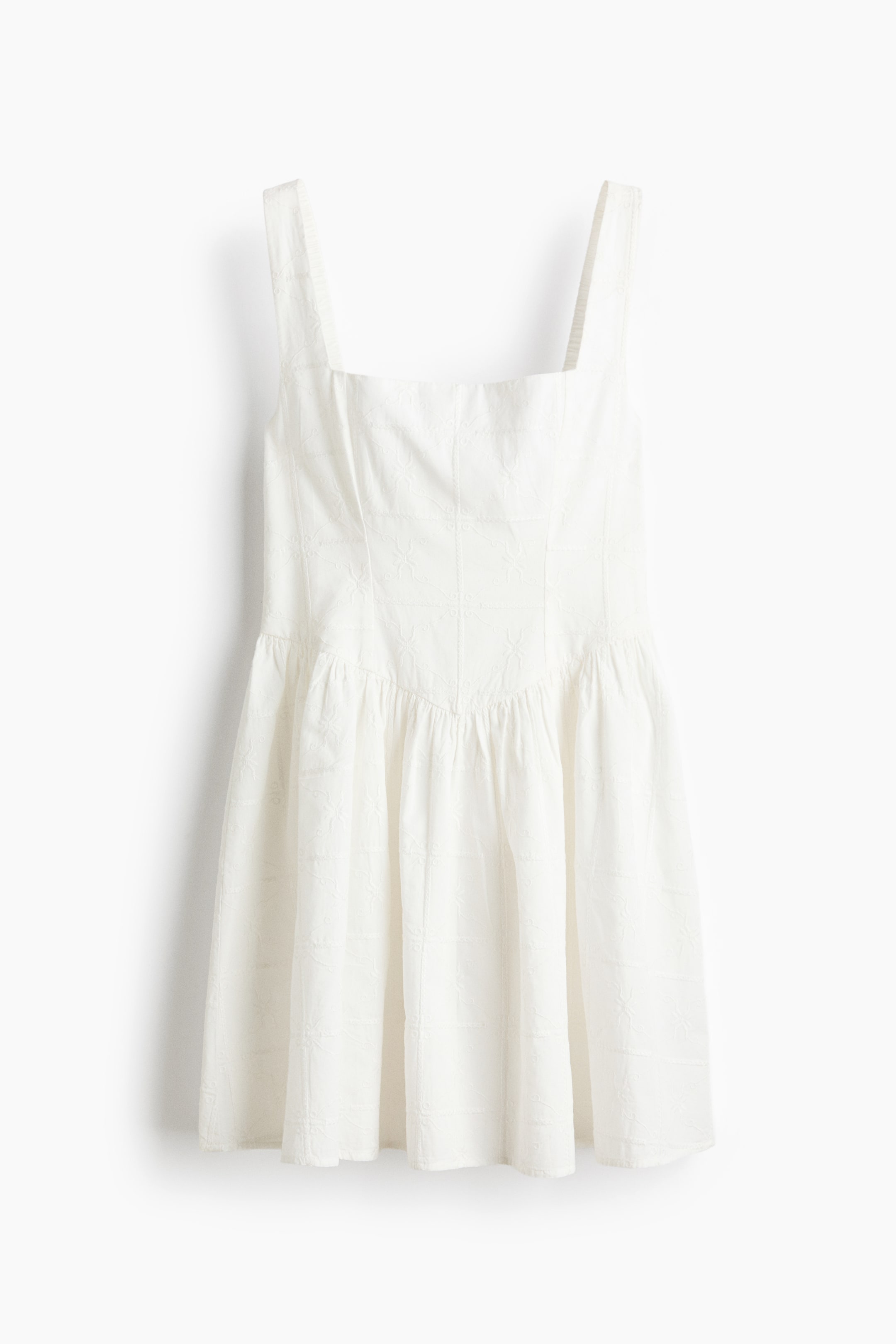 View larger image: The white mini dress features a square neckline and wide shoulder straps, with a fitted bodice transitioning into a gathered, full skirt from a high waistline. The fabric displays a subtle, embossed pattern of small squares and floral motifs.