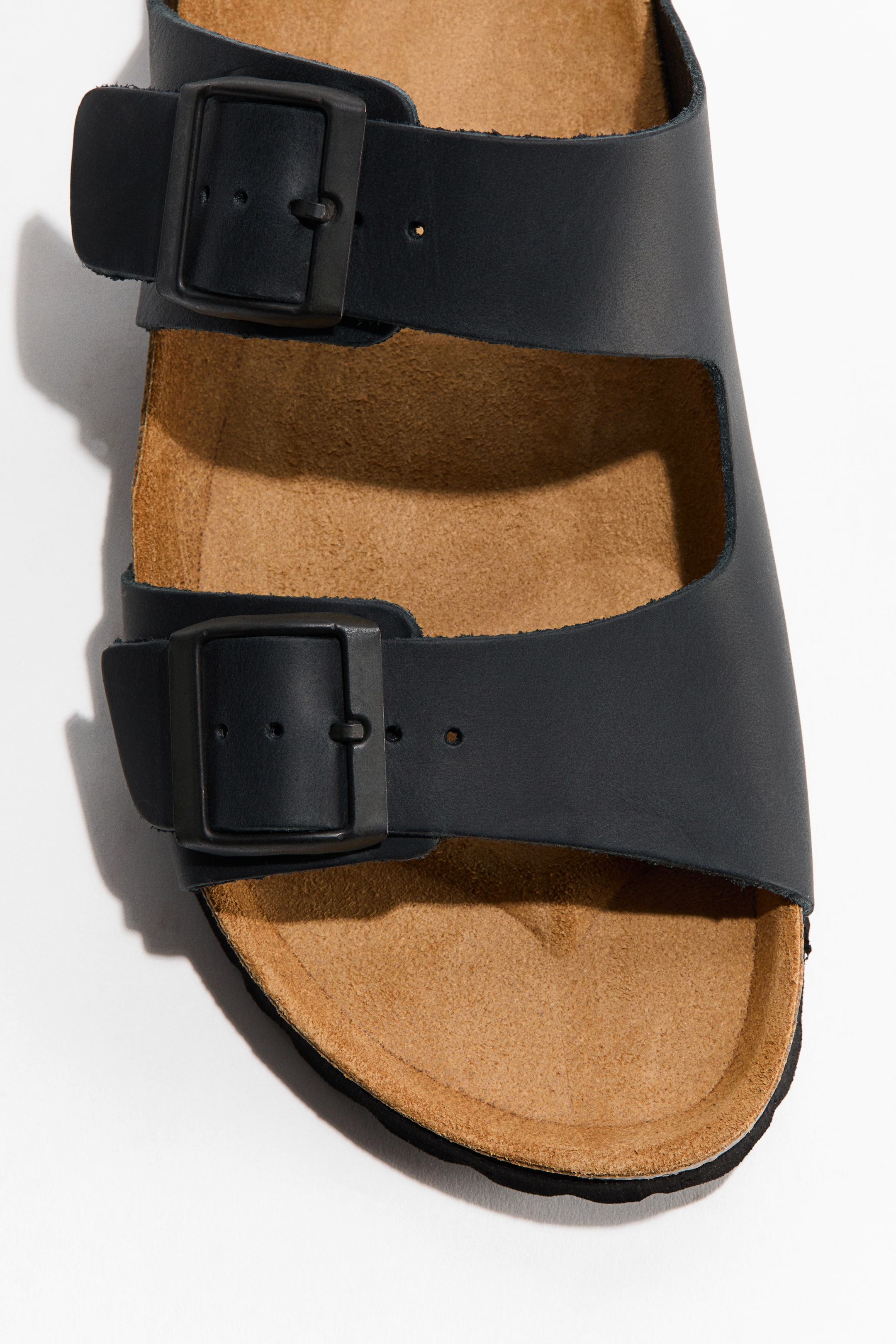 Visualizza immagine più grande: I sandali presentano due cinturini in morbida pelle nera, ciascuno con una fibbia nera regolabile. I cinturini poggiano su una soletta sagomata in camoscio color cuoio.