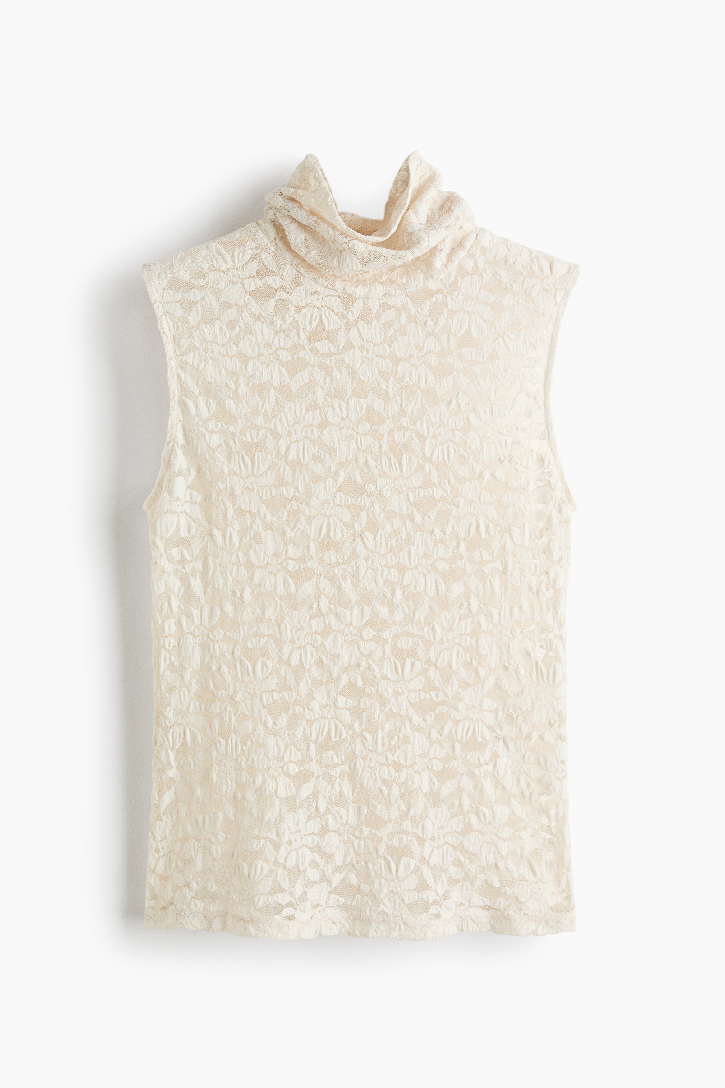 A sleeveless, fitted lace top in cream is being worn by the model, featuring a high neck and a straight-cut hem. The semi-sheer, floral-patterned top is styled with wide-leg blue jeans and a brown belt.