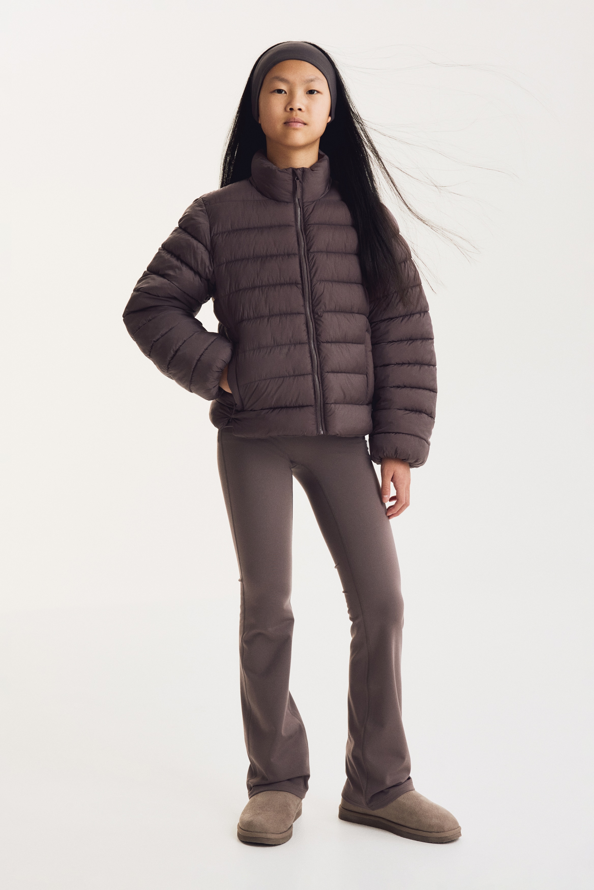 A pair of high-waisted, wide-leg trousers in a dusty mauve colour is hanging front-facing, showing a wide, flat waistband and a smooth, fitted upper section that flares out towards the hems.
