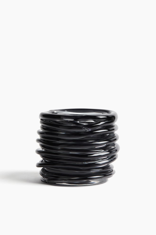A black glass tealight holder stands elegantly, showcasing a sculptural, coiled design. Its cylindrical shape is crafted from multiple stacked, smooth rings of glass. - 1
